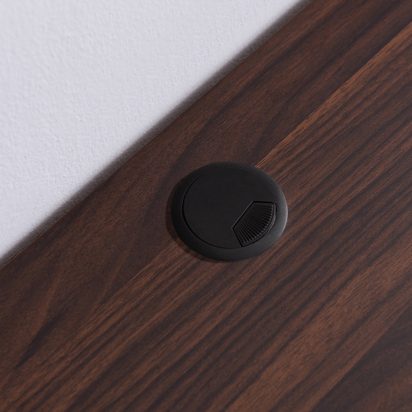Right angled close-up of cord management on a modern black and cappuccino cube and open shelf floating TV stand on a white wall