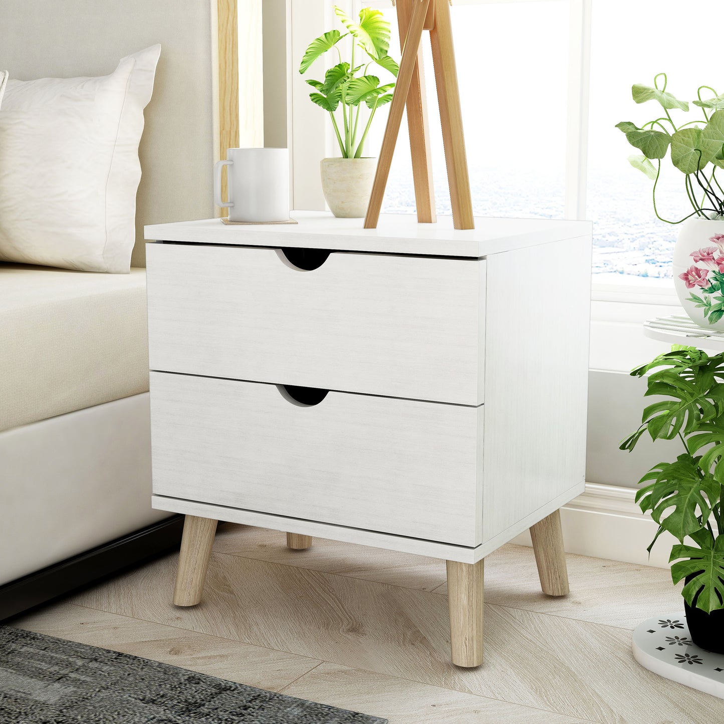 Left angled mid-century modern white two-drawer nightstand in a bedroom with accessories