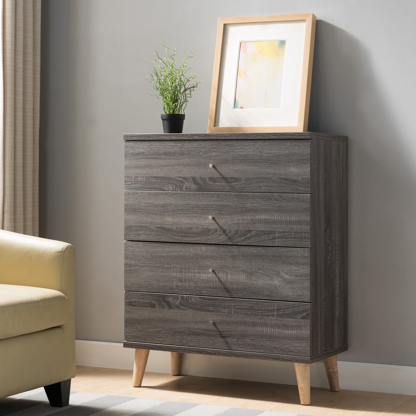 Left angled mid-century modern distressed gray four-drawer chest dresser in a living area with accessories