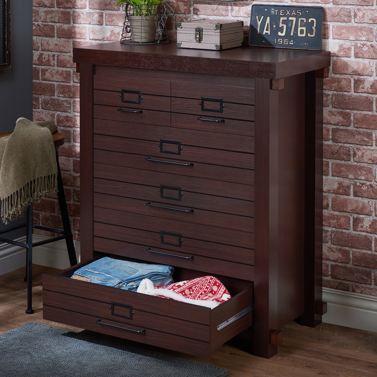 Left angled rustic espresso six-drawer plank chest dresser with bottom drawer open in a living space with accessories