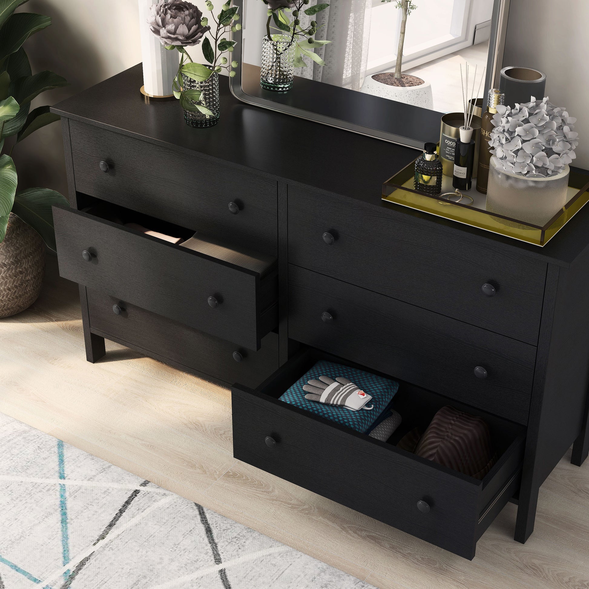 Left angled bird's eye view of a transitional black six-drawer youth dresser with two drawers open in a bedroom with accessories