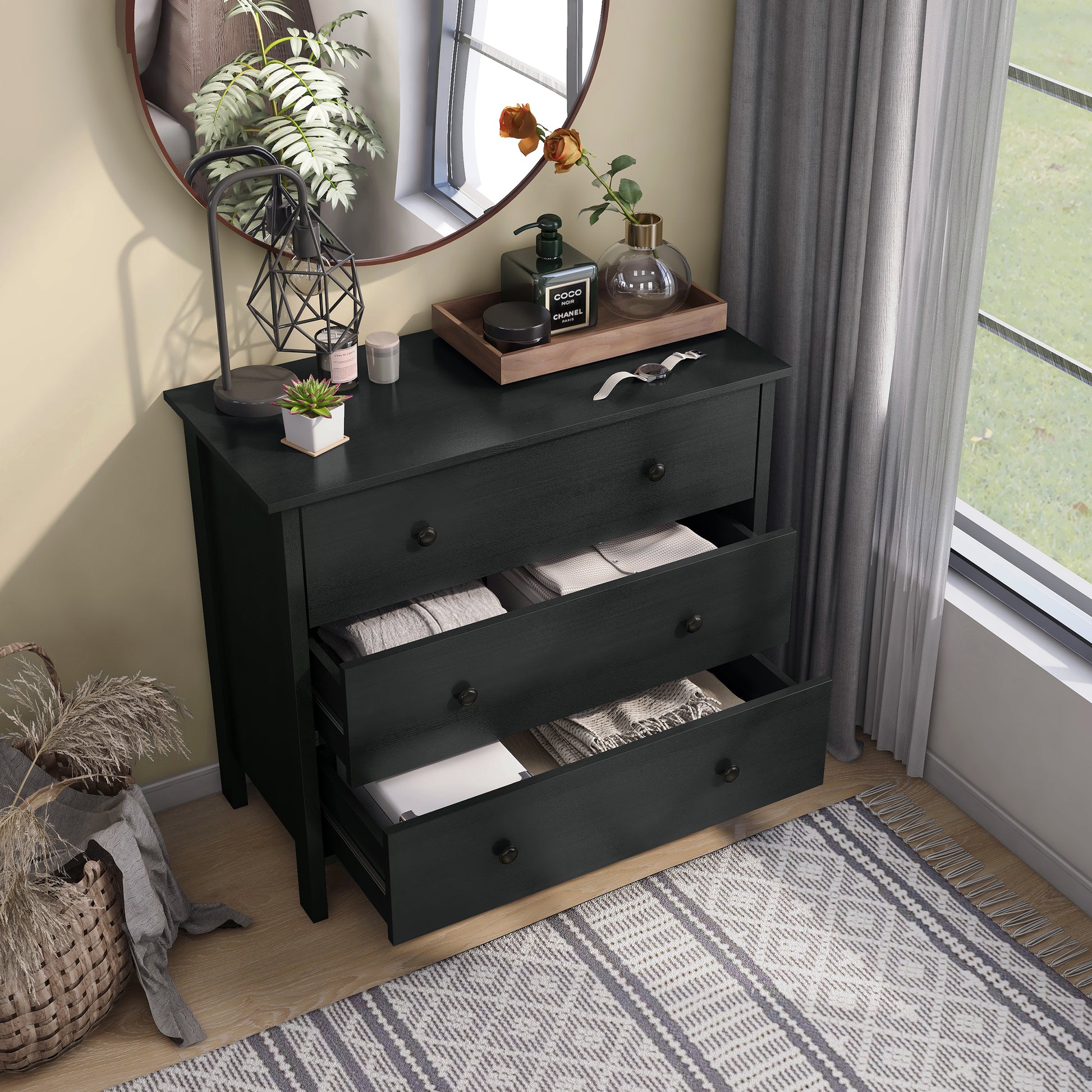 Right angled bird's eye view of a transitional black three-drawer youth dresser with two drawers open in a bedroom with accessories
