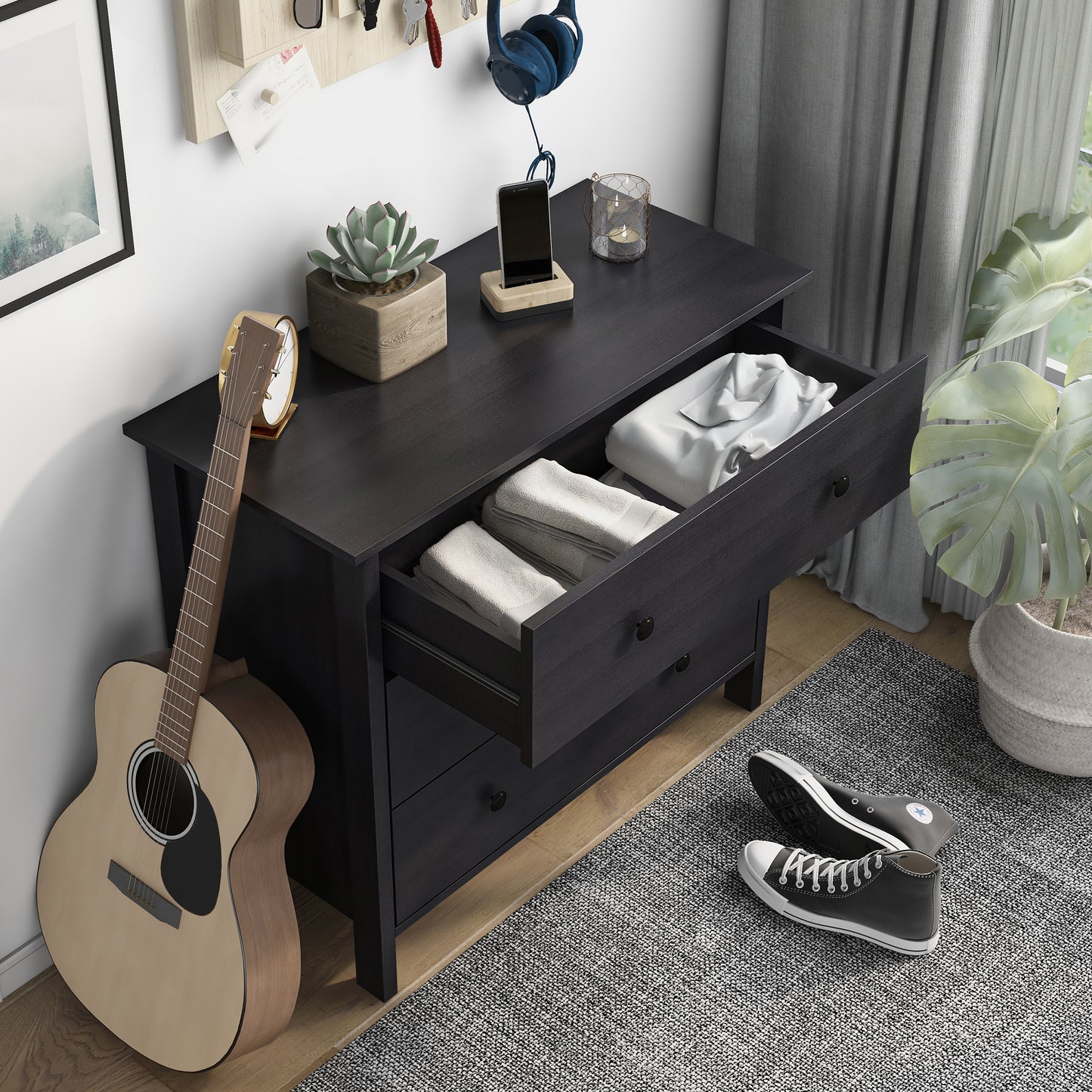 Right angled bird's eye view of a transitional black three-drawer youth dresser with top drawers open in a bedroom with accessories