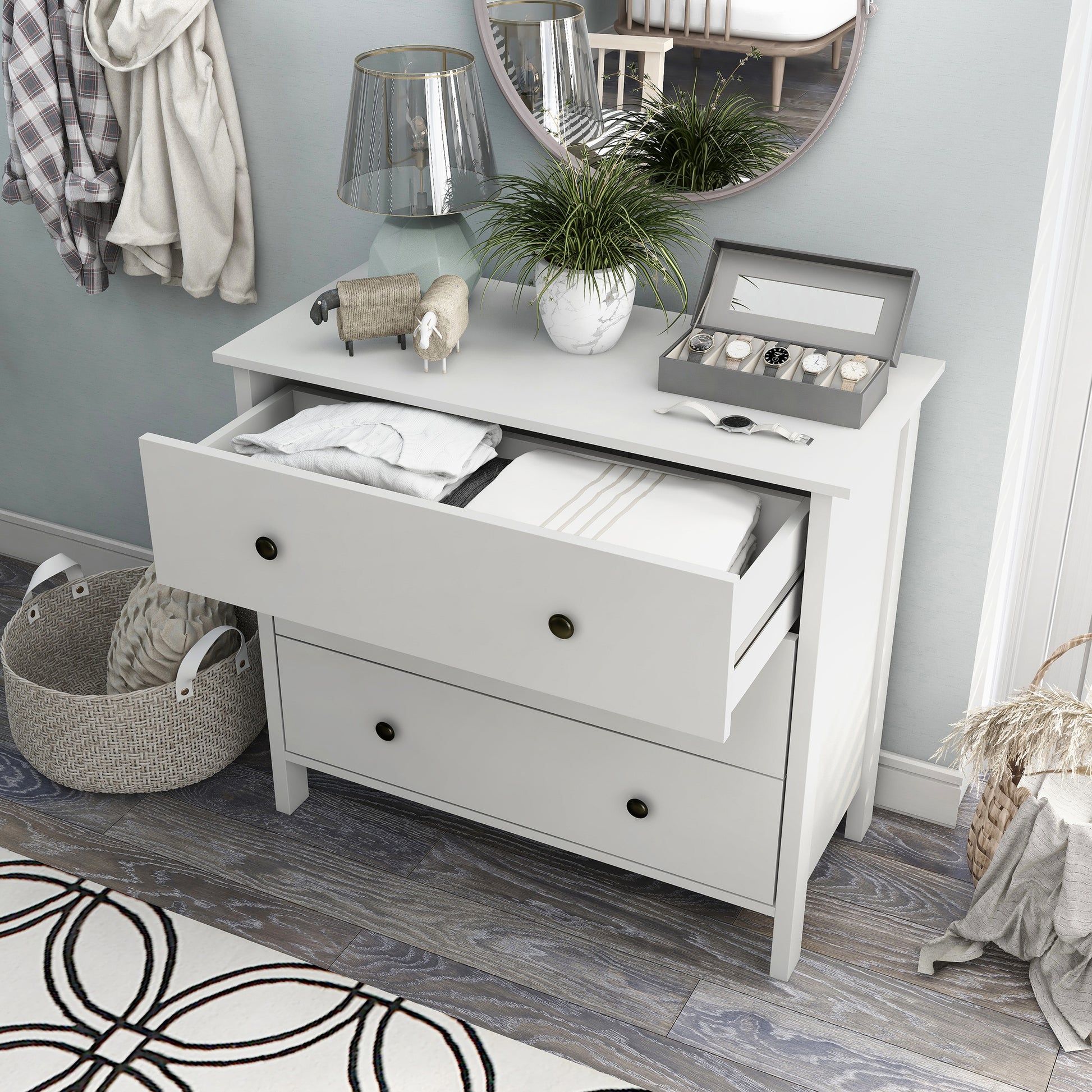 Left angled bird's eye view of a transitional white three-drawer youth dresser with top drawer open in a bedroom with accessories