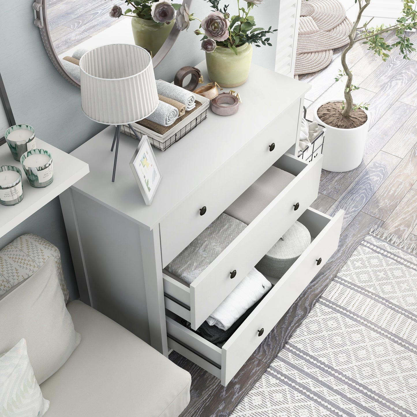 Right angled bird's eye view of a transitional white three-drawer youth dresser with two drawers open in a bedroom with accessories