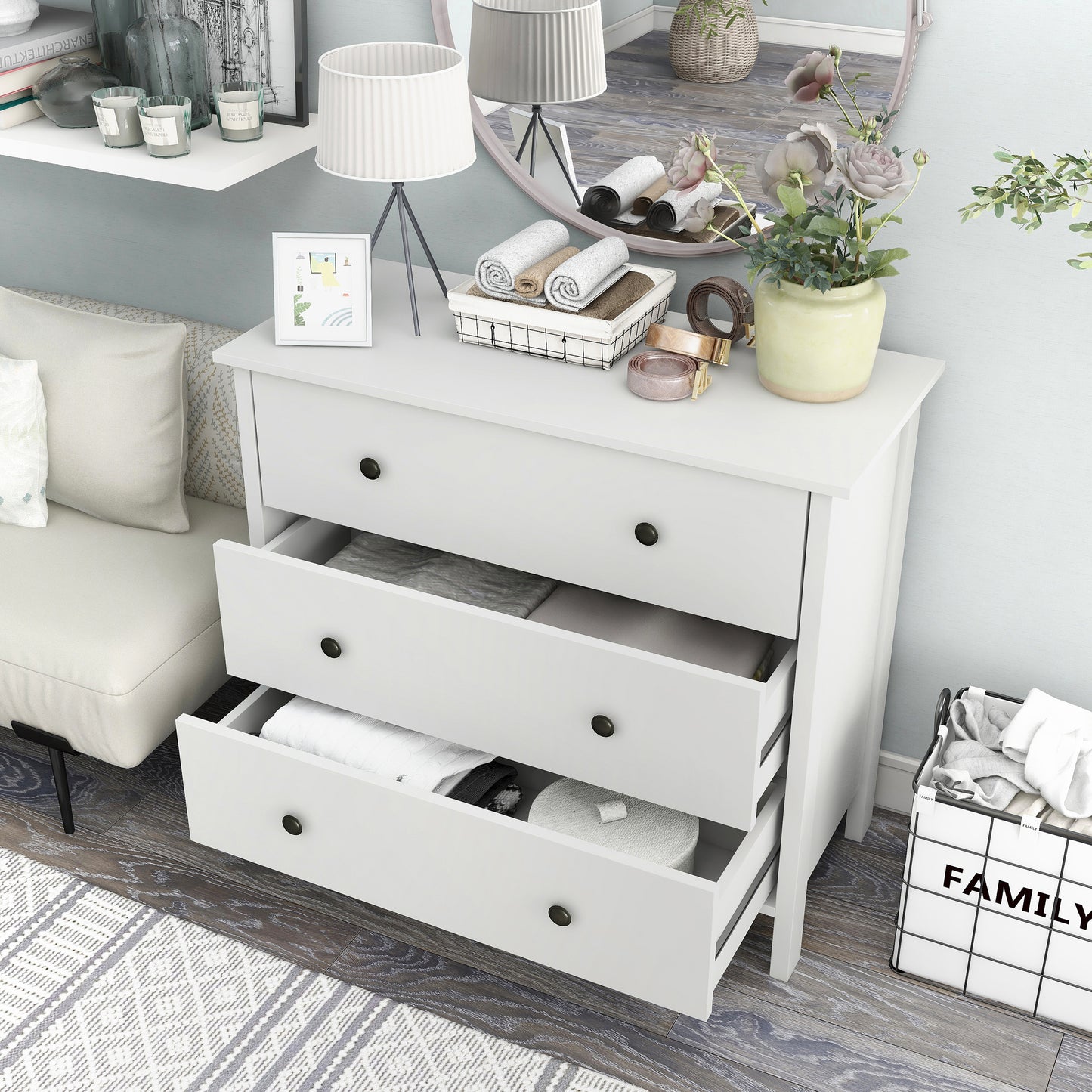 Left angled bird's eye view of a transitional white three-drawer youth dresser with two drawers open in a bedroom with accessories