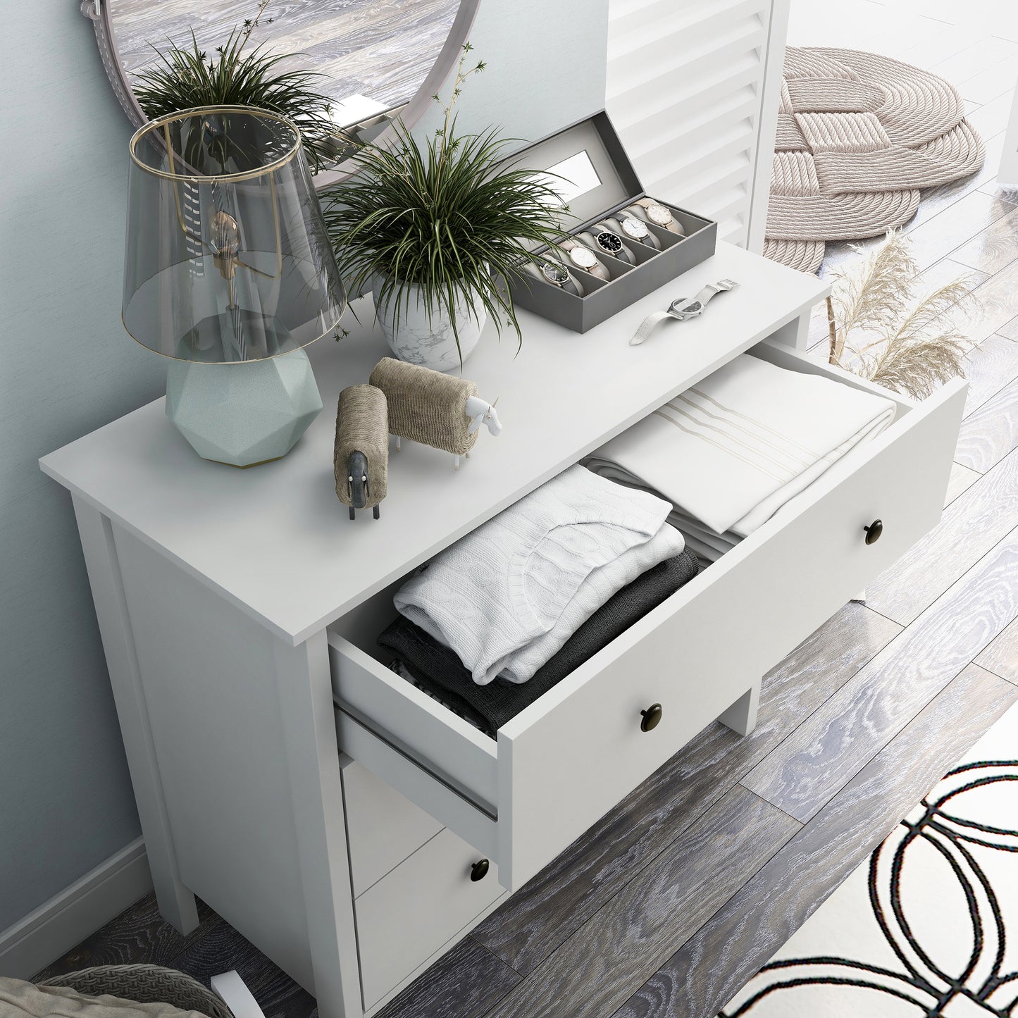 Right angled bird's eye view of a transitional white three-drawer youth dresser with top drawer open in a bedroom with accessories