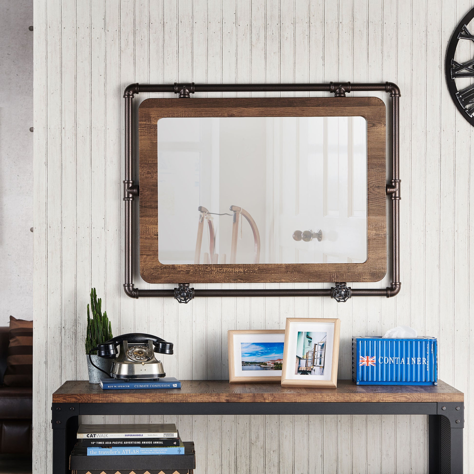 Front-facing industrial reclaimed oak and water pipe wall mirror over a table with accessories