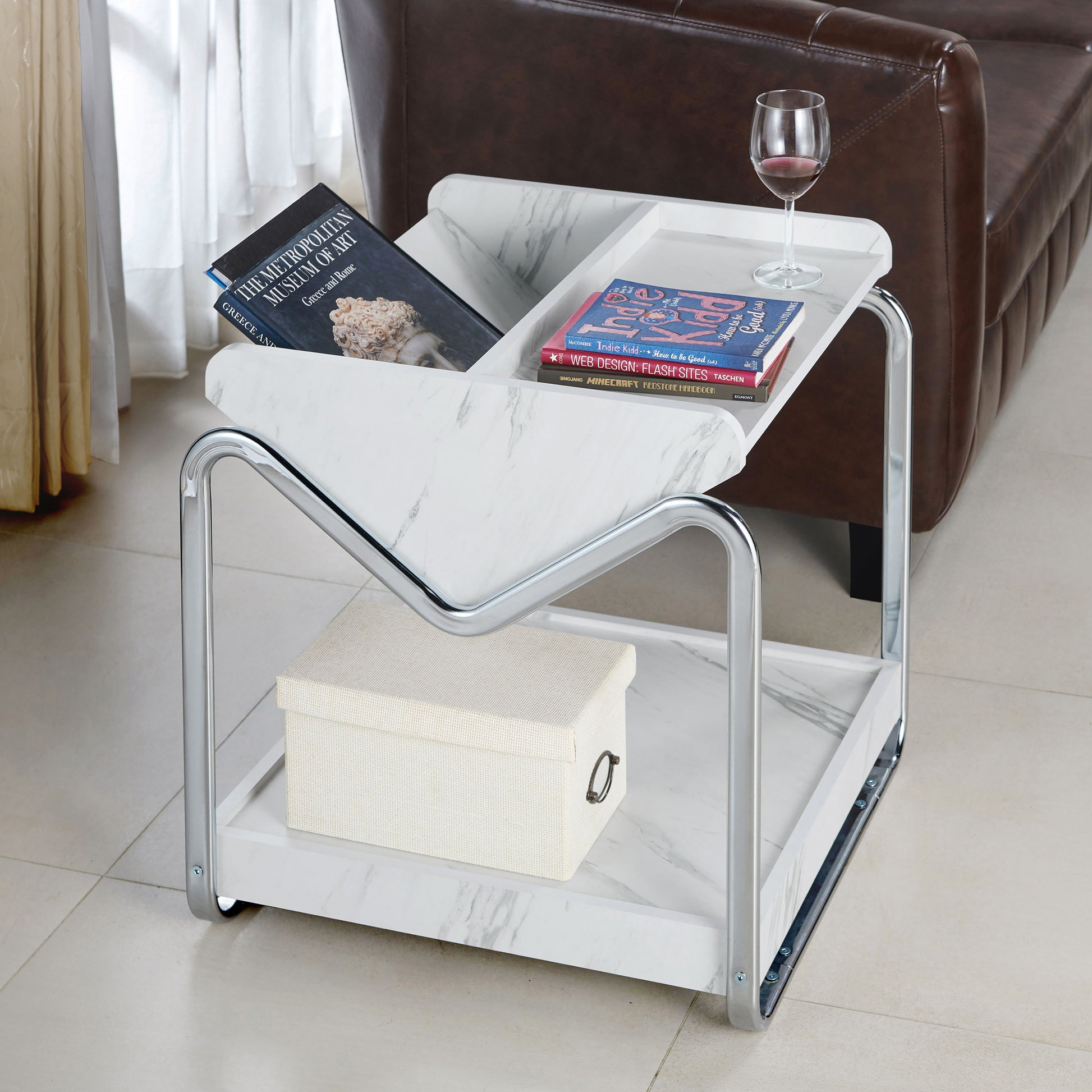 Right angled contemporary faux white marble and chrome three-shelf end table in a living room with accessories