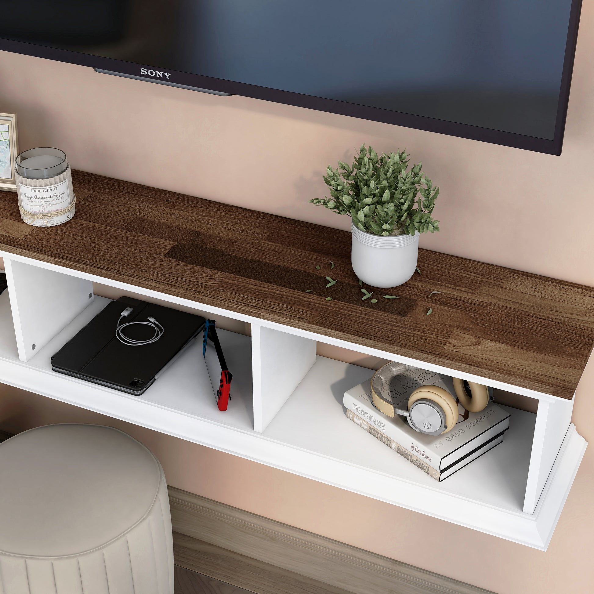 Left angled upper view tabletop close up of a transitional light hickory and white floating TV stand with three shelves in a living room with accessories