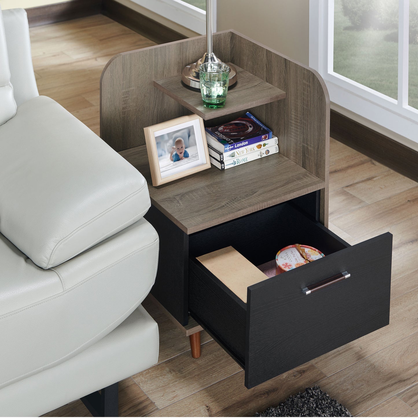 Right angled upper view of a contemporary chestnut brown one-drawer nightstand with a mini shelf and drawer open in a living room with accessories