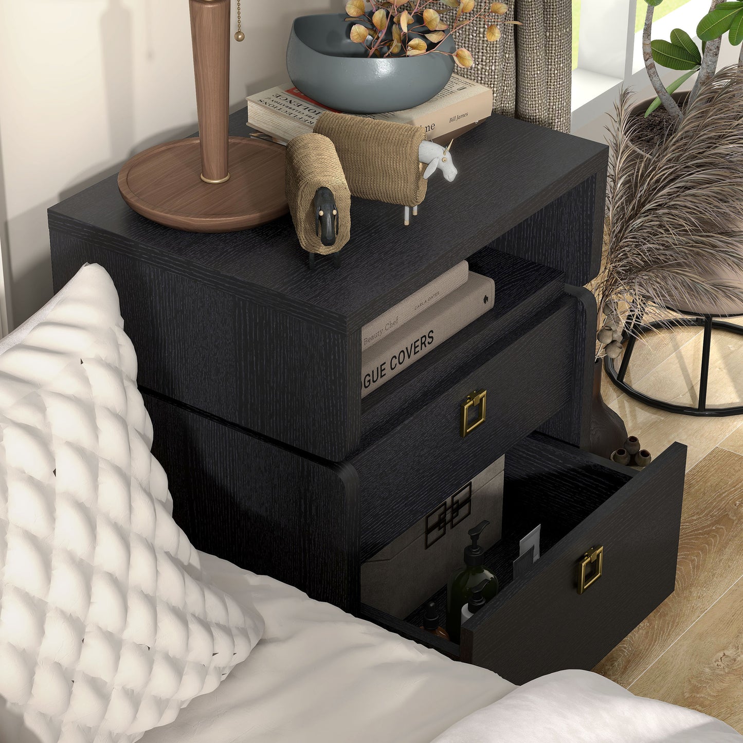 Right angled upper view of a modern black two-drawer nightstand/end table with lower drawer open in a bedroom with accessories