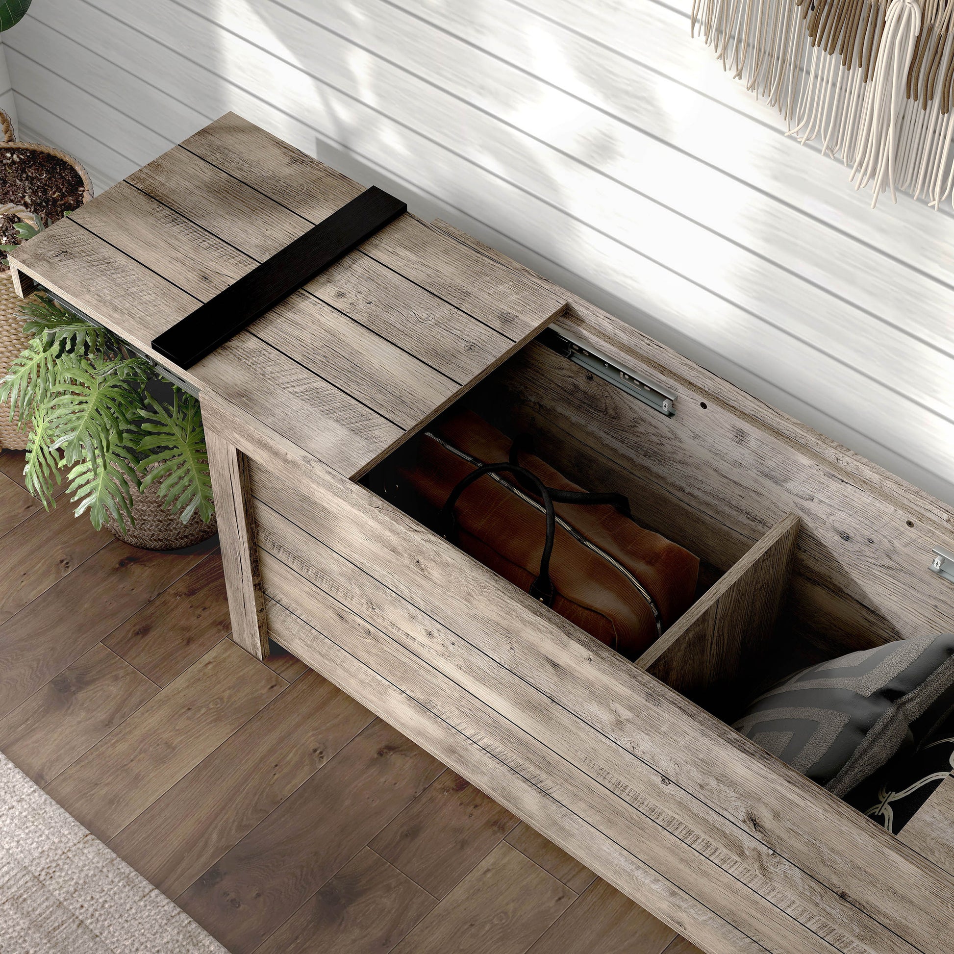 Left angled bird's eye view of a farmhouse weathered oak sliding top storage bench with top open in an entryway with accessories