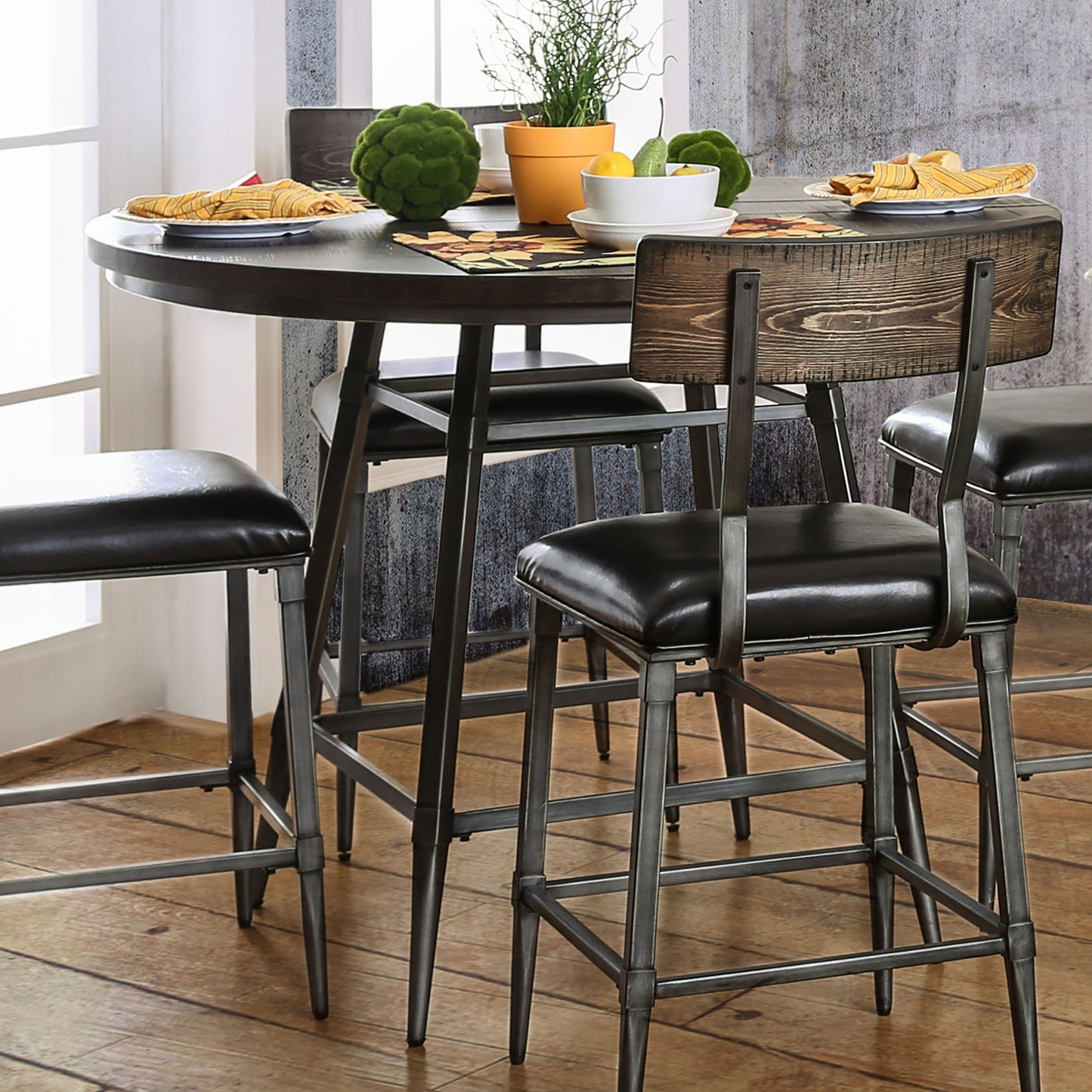 Angled rustic industrial weathered gray and rustic dark oak counter height round dining table in a dining area with chairs and accessories