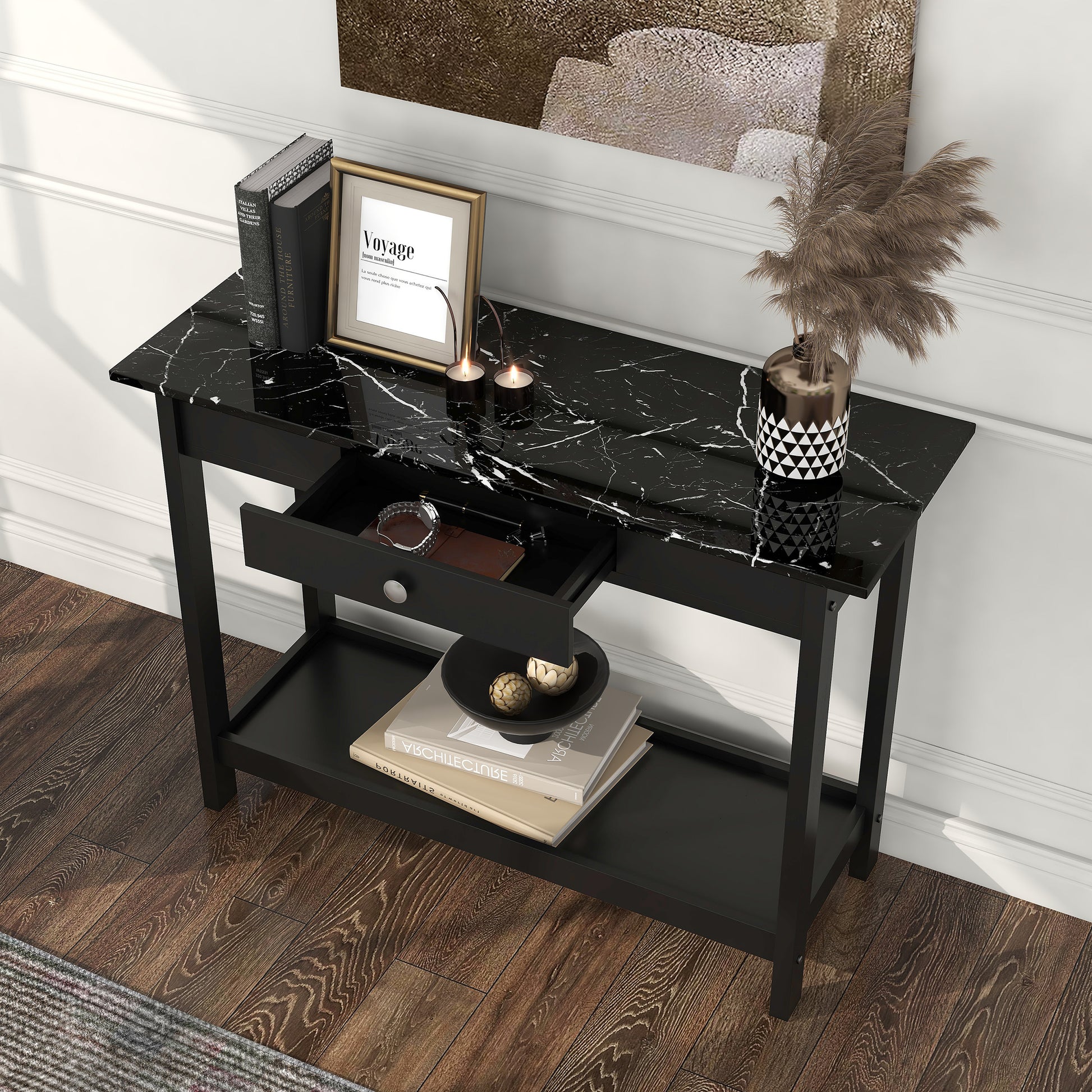 Left angled bird's eye view of a modern black and faux marble one-drawer console table with a lower shelf and drawer open in a living area with accessories