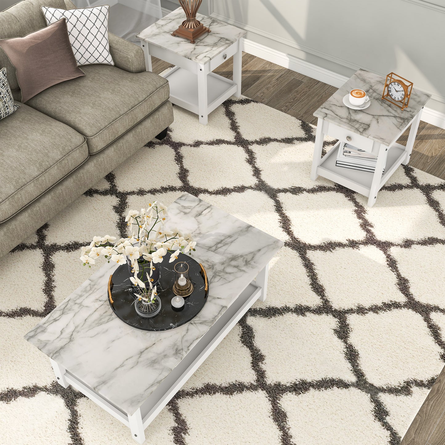 Right angled bird's eye view of a three-piece modern white and faux marble coffee table set with lower shelves in a living area with accessories