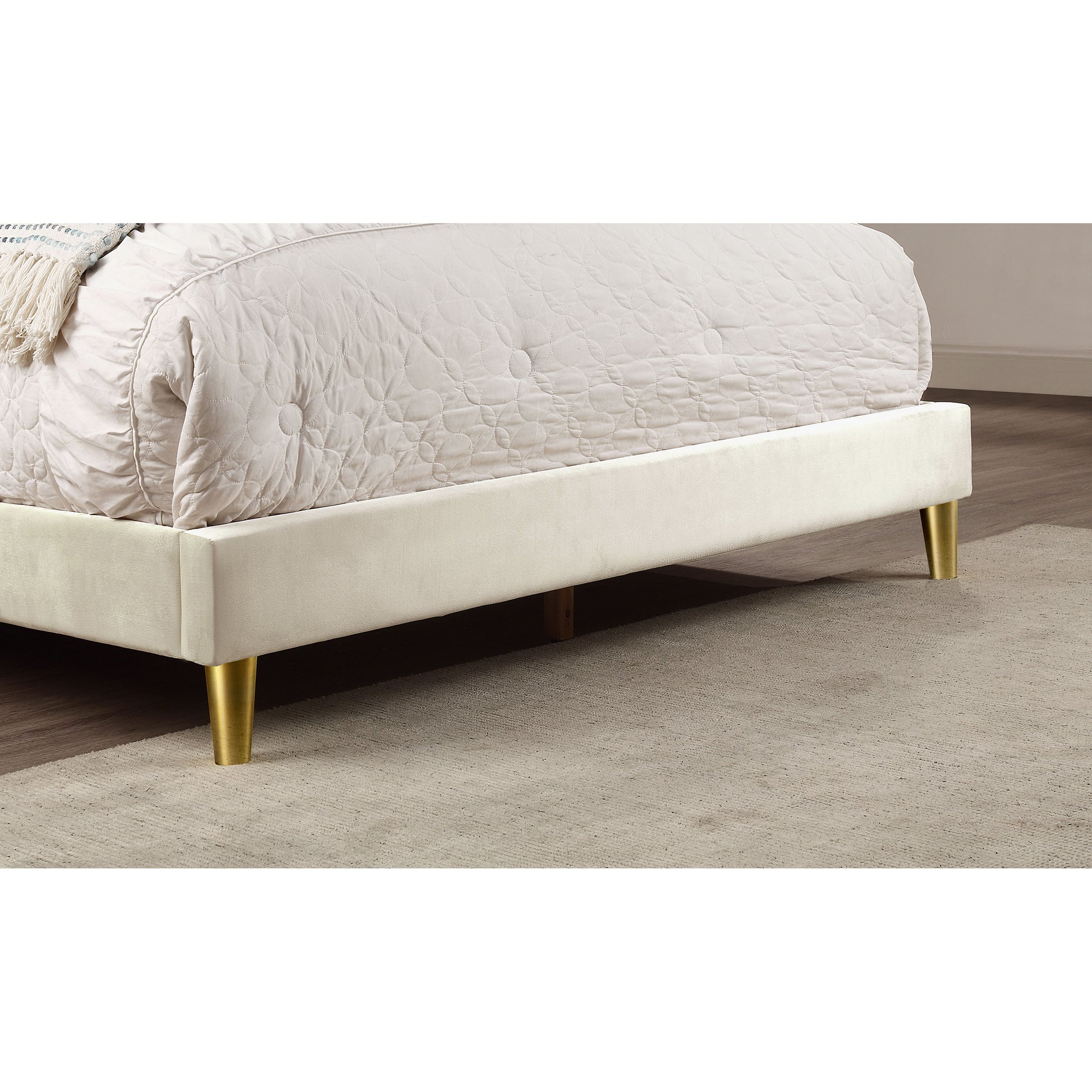 Right angled footboard close-up of a contemporary beige and gold upholstered eastern king bed in a bedroom with accessories