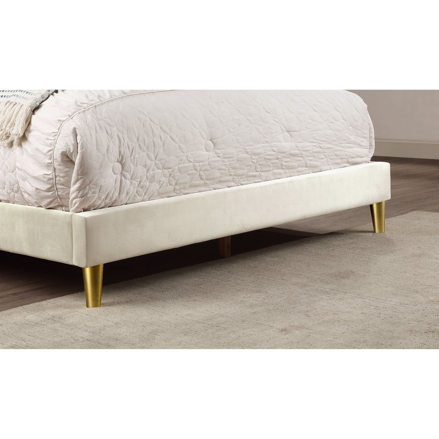 Right angled footboard close-up of a contemporary beige and gold upholstered full bed in a bedroom with accessories