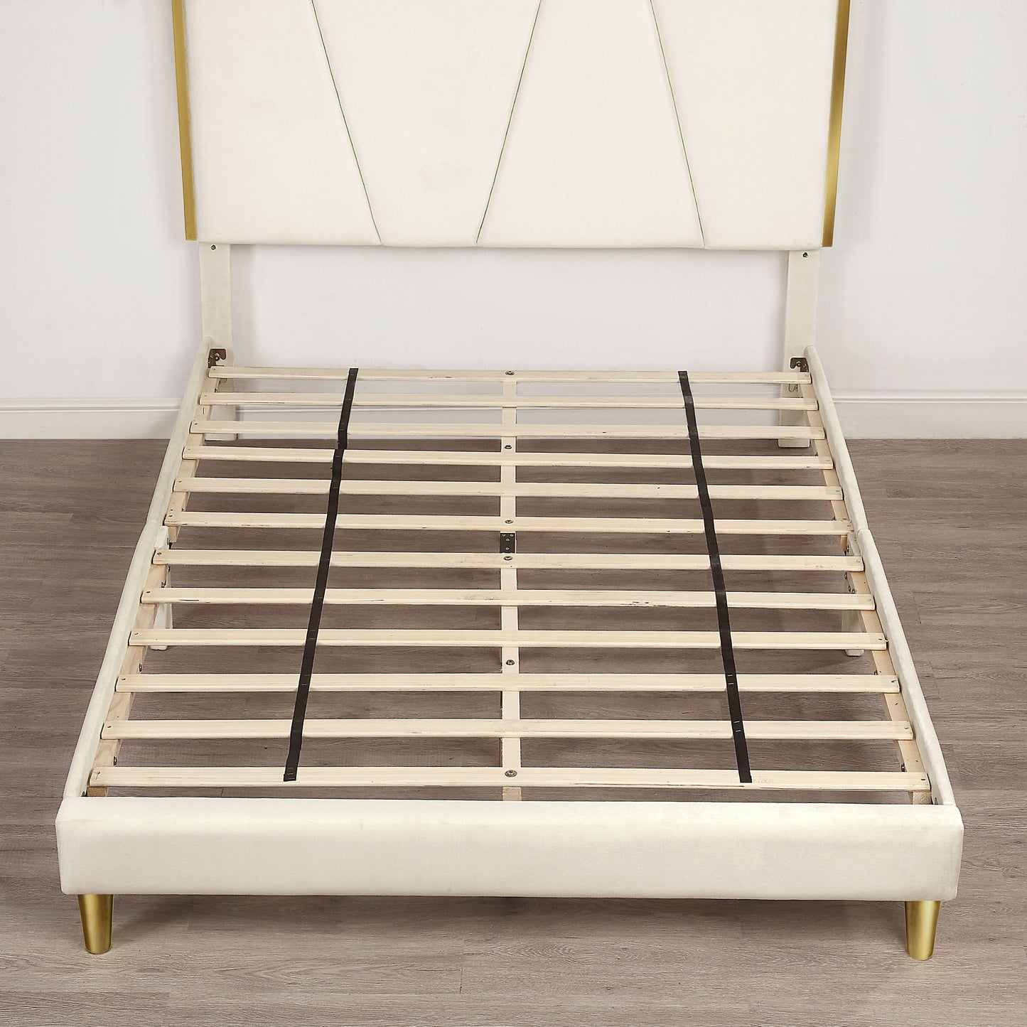 Front-facing contemporary beige and gold upholstered queen bed with slats shown in an empty room with wood floors