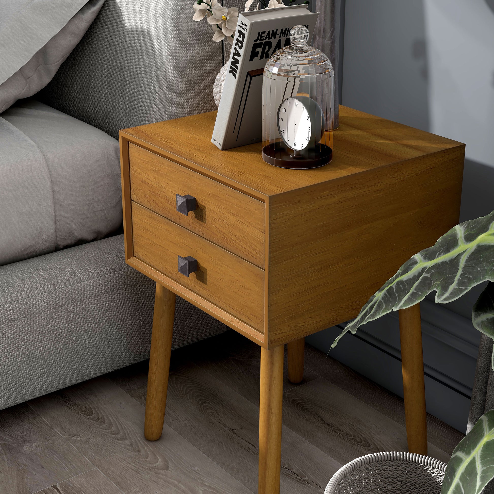 Left angled modern light oak two-drawer compact nightstand with splayed legs in a bedroom with accessories