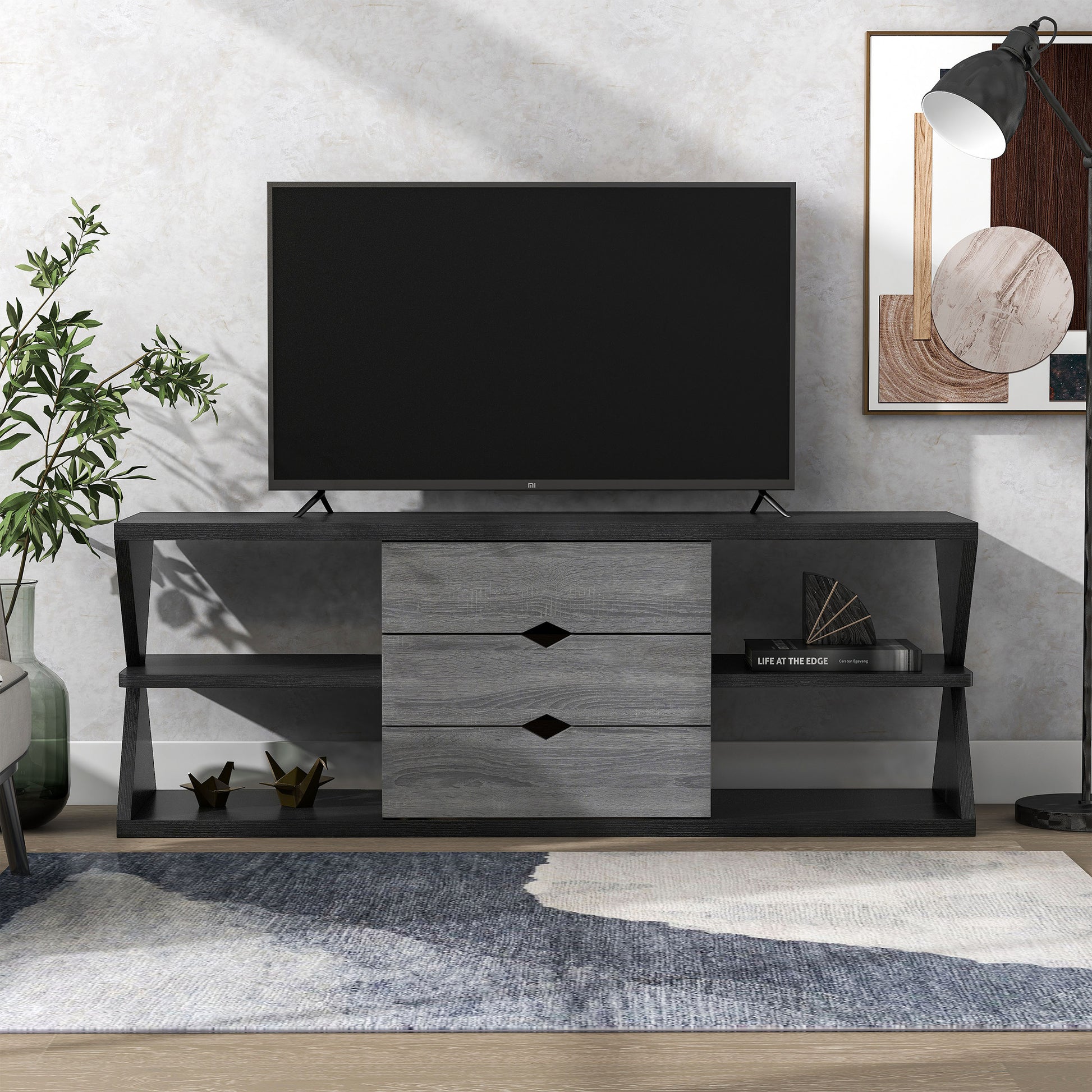 Front-facing modern black and distressed gray three-drawer TV stand in a living area with accessories