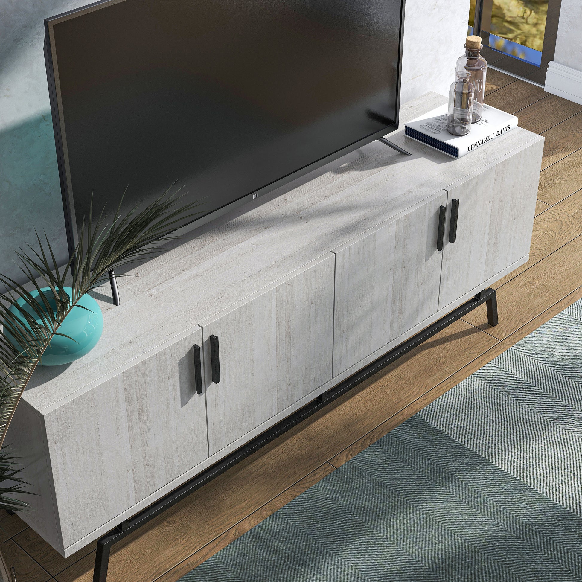 Right angled bird's eye view of a modern white oak and black four-door TV stand in a living room with accessories