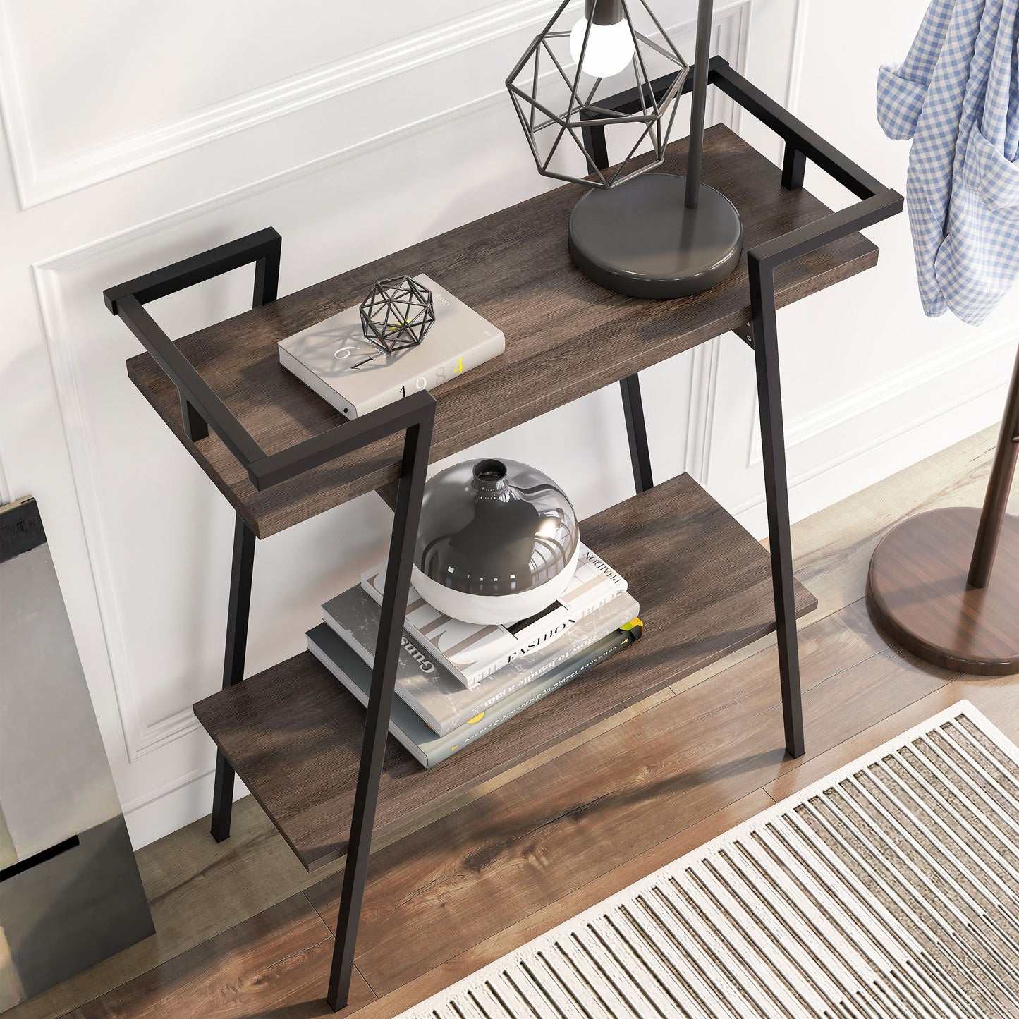 Right angled bird's eye view of a urban industrial walnut oak and black two-shelf geometric console table in an entry with accessories