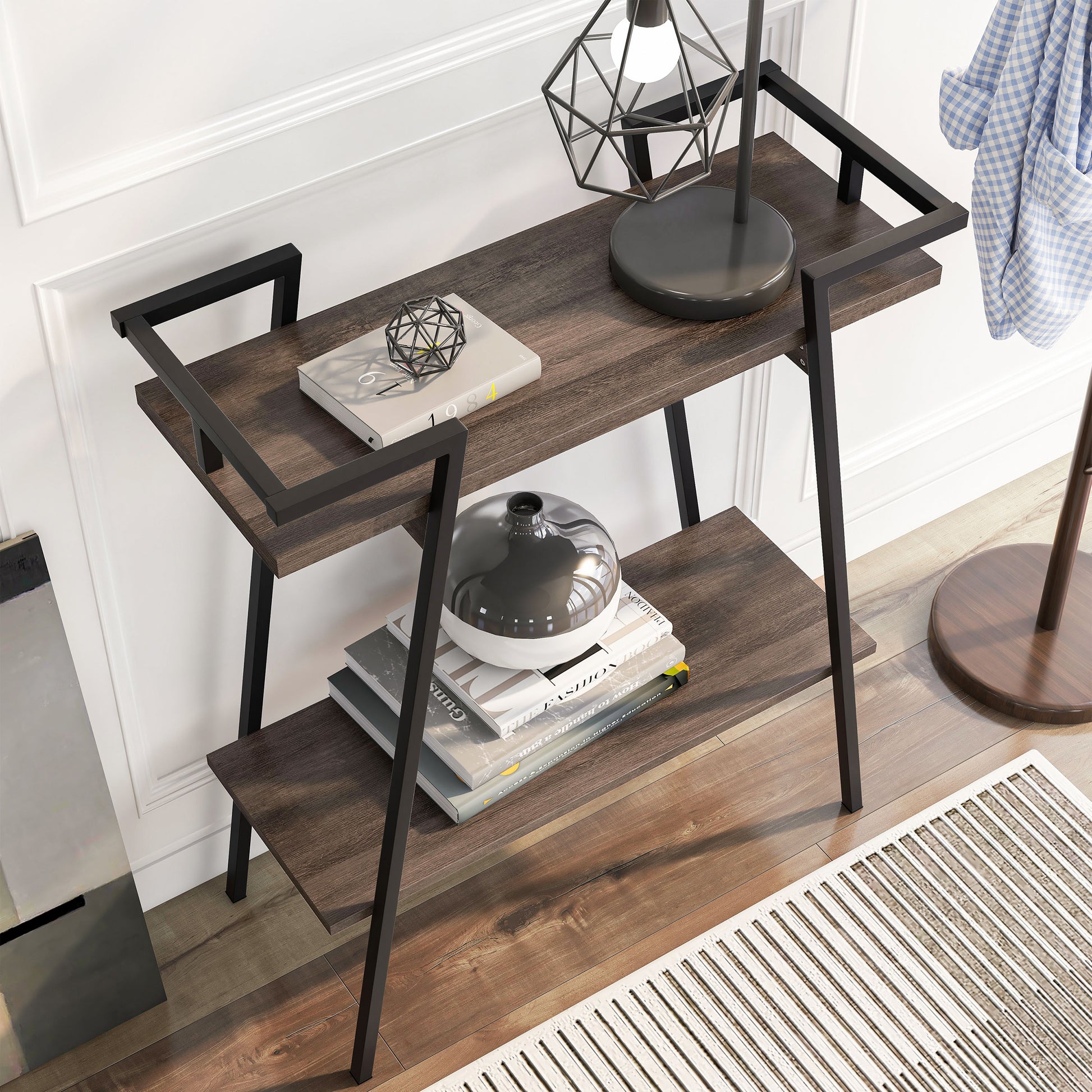 Right angled bird's eye view of a urban industrial walnut oak and black two-shelf geometric console table in an entry with accessories