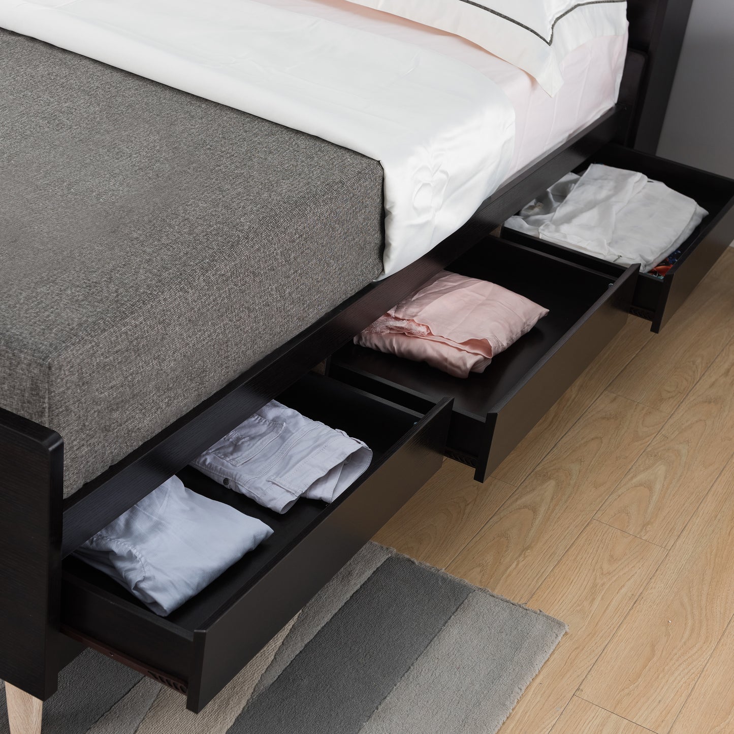 Right angled close-up of a contemporary cappuccino three-drawer queen platform bed with drawers open in a bedroom with linens
