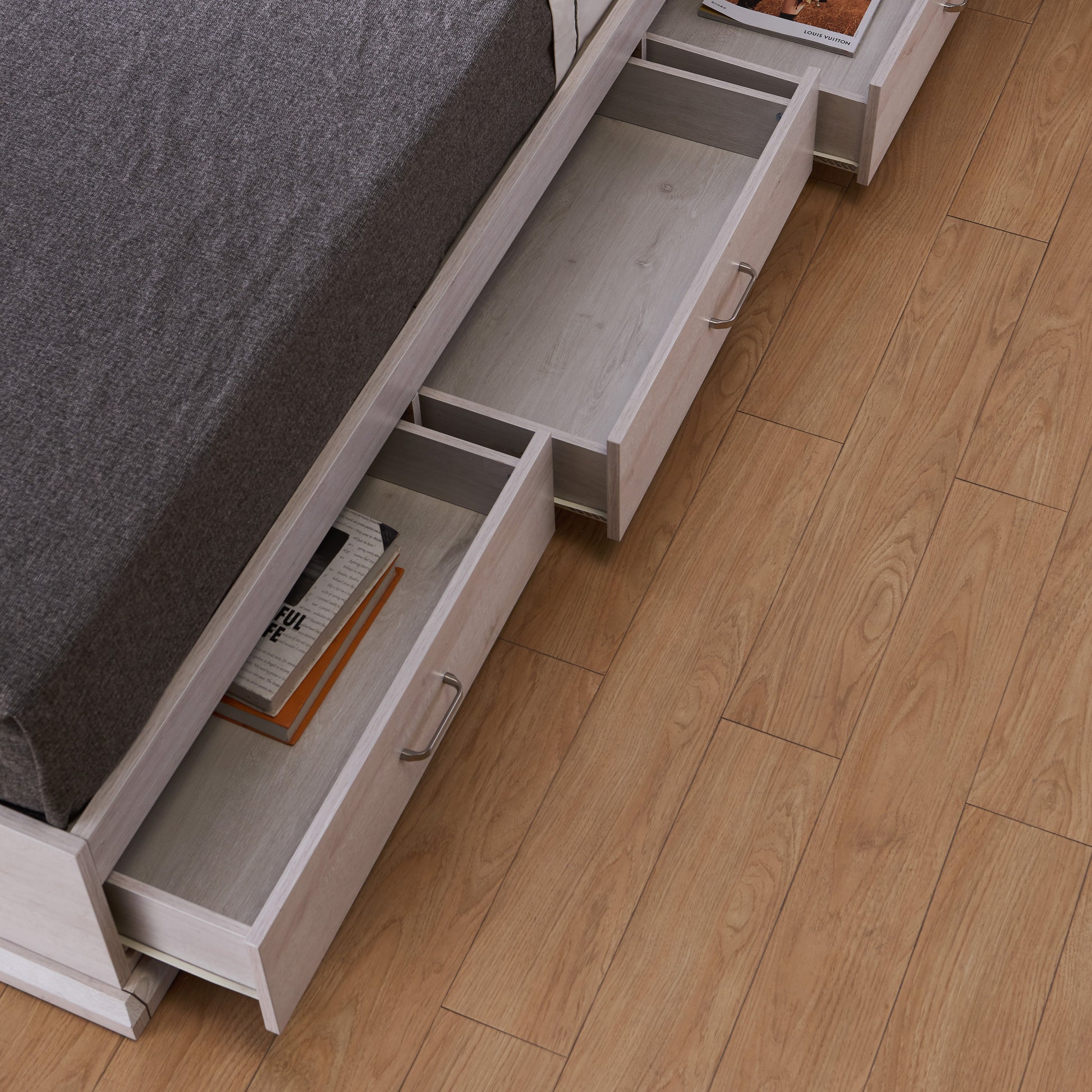 Left angled bird's eye open drawer close-up view of a contemporary three-drawer storage bed in a bedroom with accessories