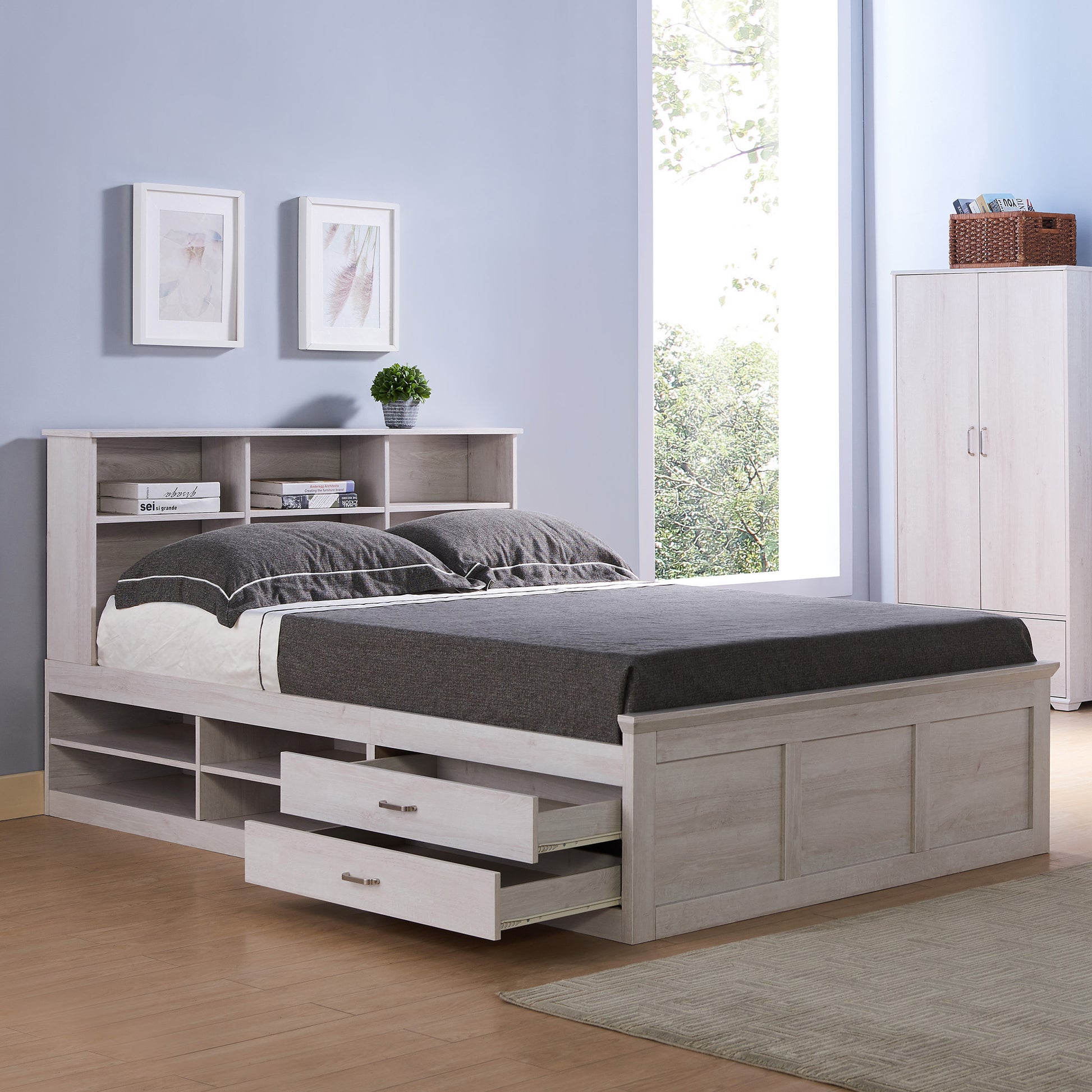 Right angled transitional white oak two-drawer four-shelf storage bed shown with optional bookcase headboard and drawers open in a bedroom with accessories