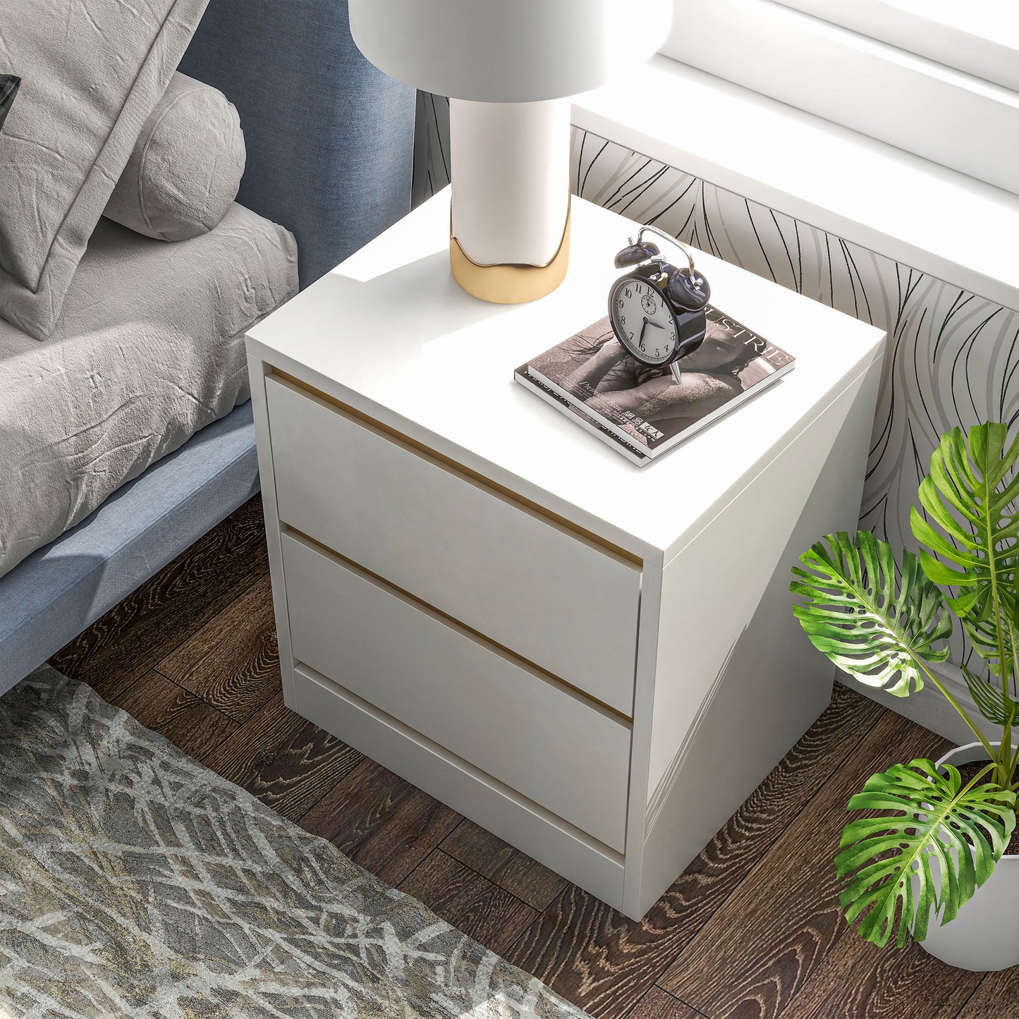 Left angled bird's eye view of a modern white and gold two-drawer nightstand in a bedroom with accessories