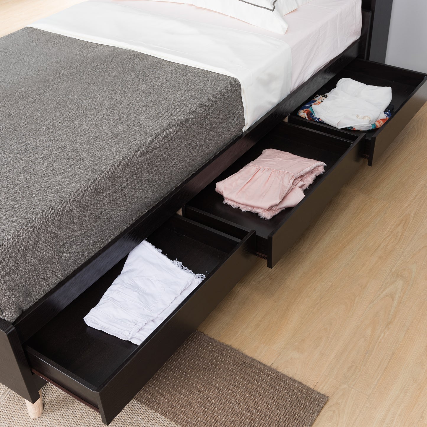 Left angled close-up contemporary cappuccino platform storage bed with a bookcase headboard with three drawers open in a bedroom with accessories
