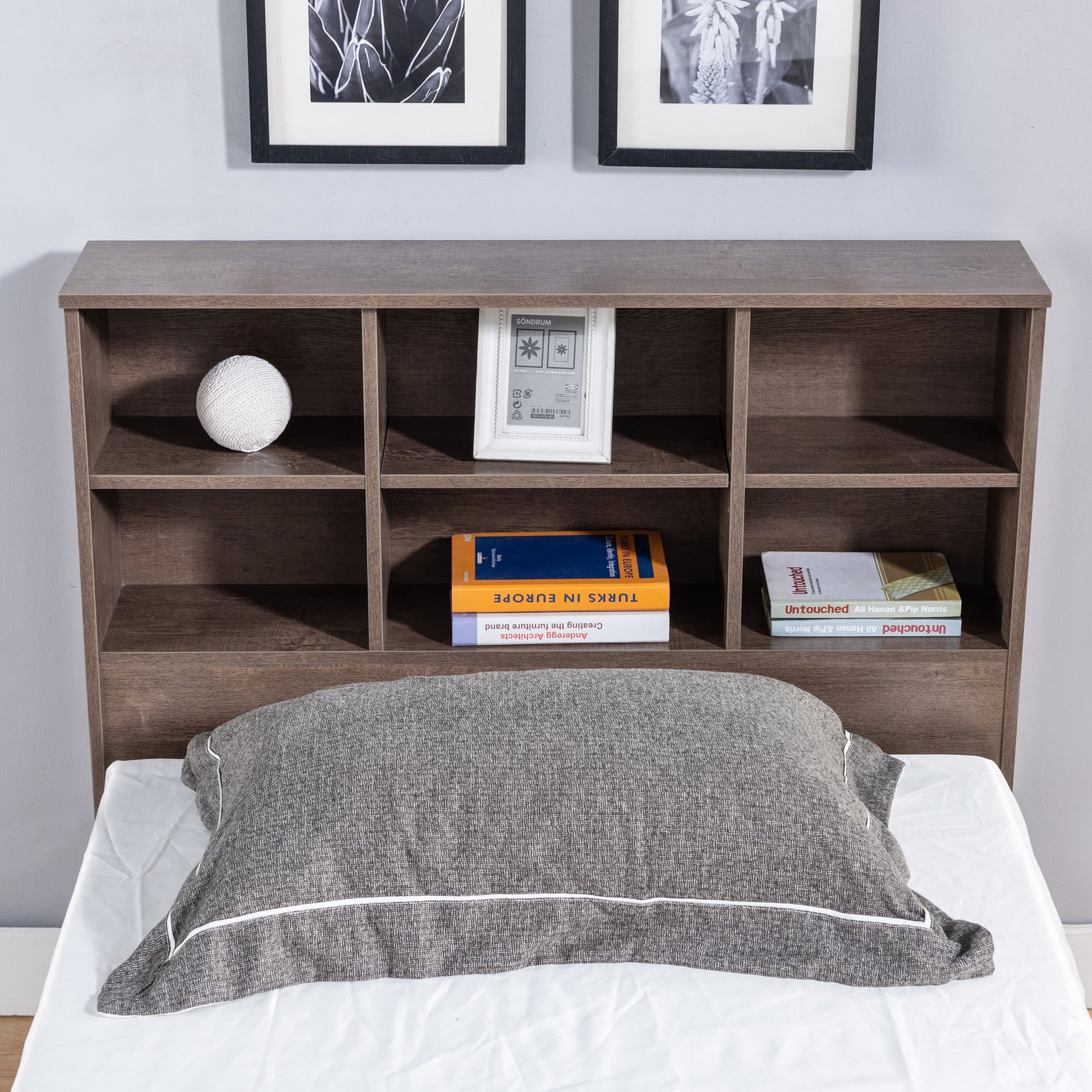 Front-facing headboard close-up of a contemporary walnut three-drawer platform storage bed with a bookcase headboard in a bedroom with accessories
