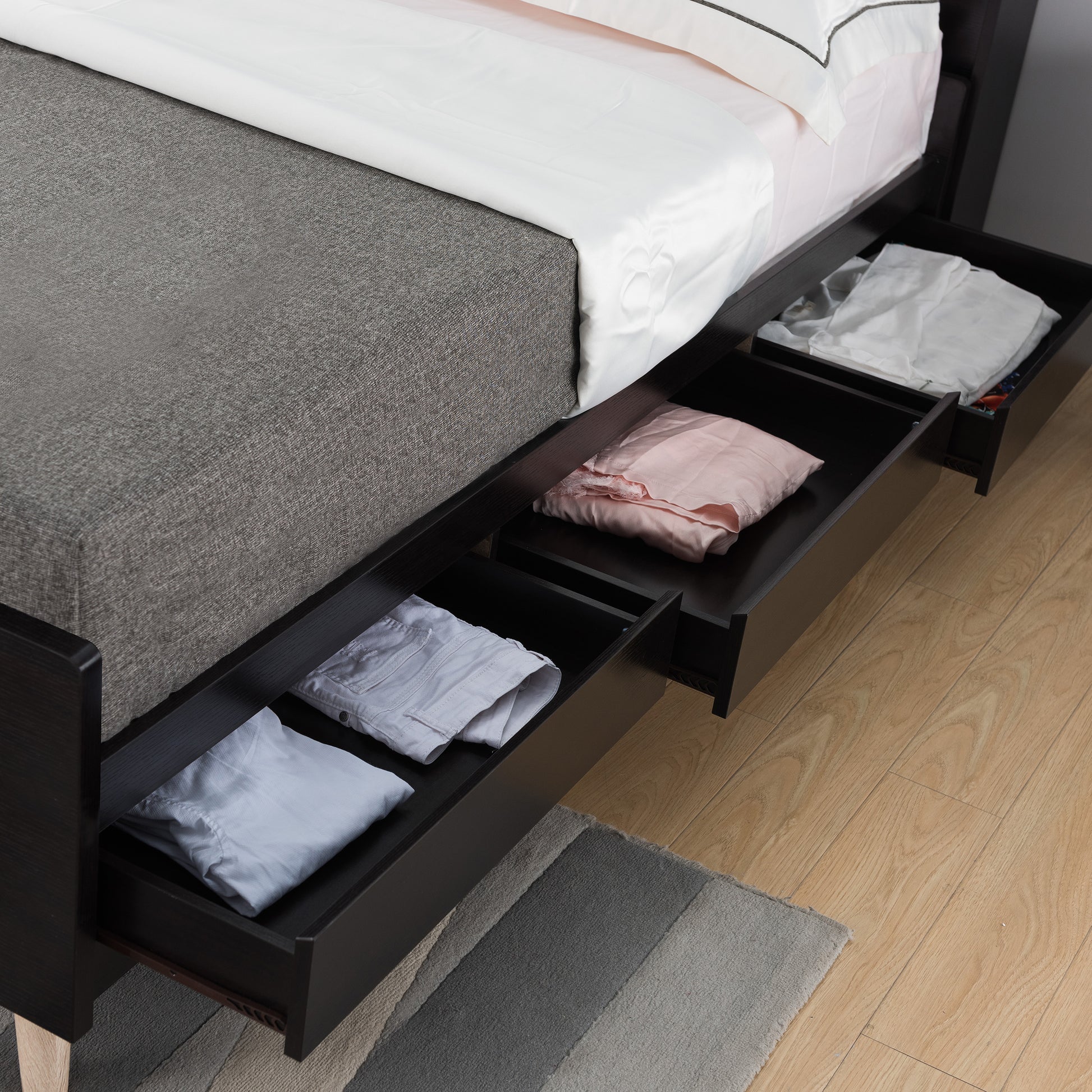 Left angled close-up of a contemporary cappuccino three-drawer platform bed with drawers open in a bedroom with accessories