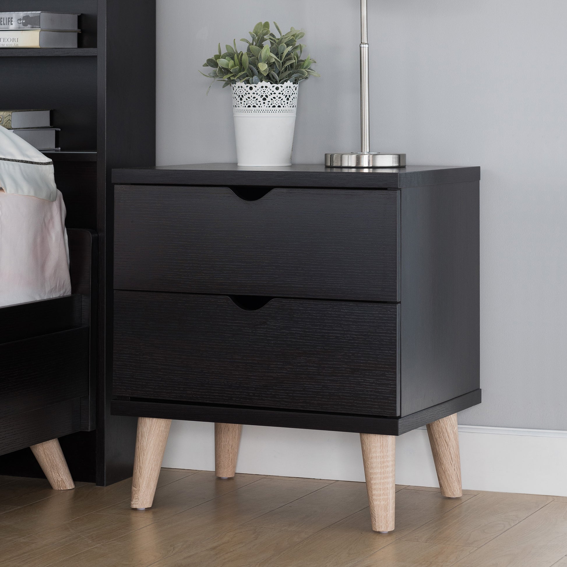 Left angled mid-century modern cappuccino two-drawer nightstand in a bedroom with accessories