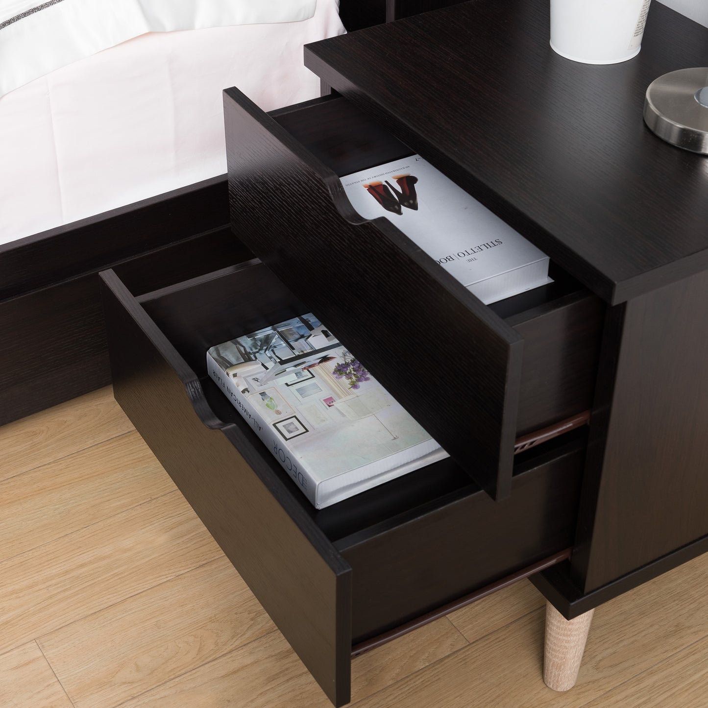 Left angled bird's eye view of a mid-century modern cappuccino two-drawer nightstand with drawers open in a bedroom with accessories