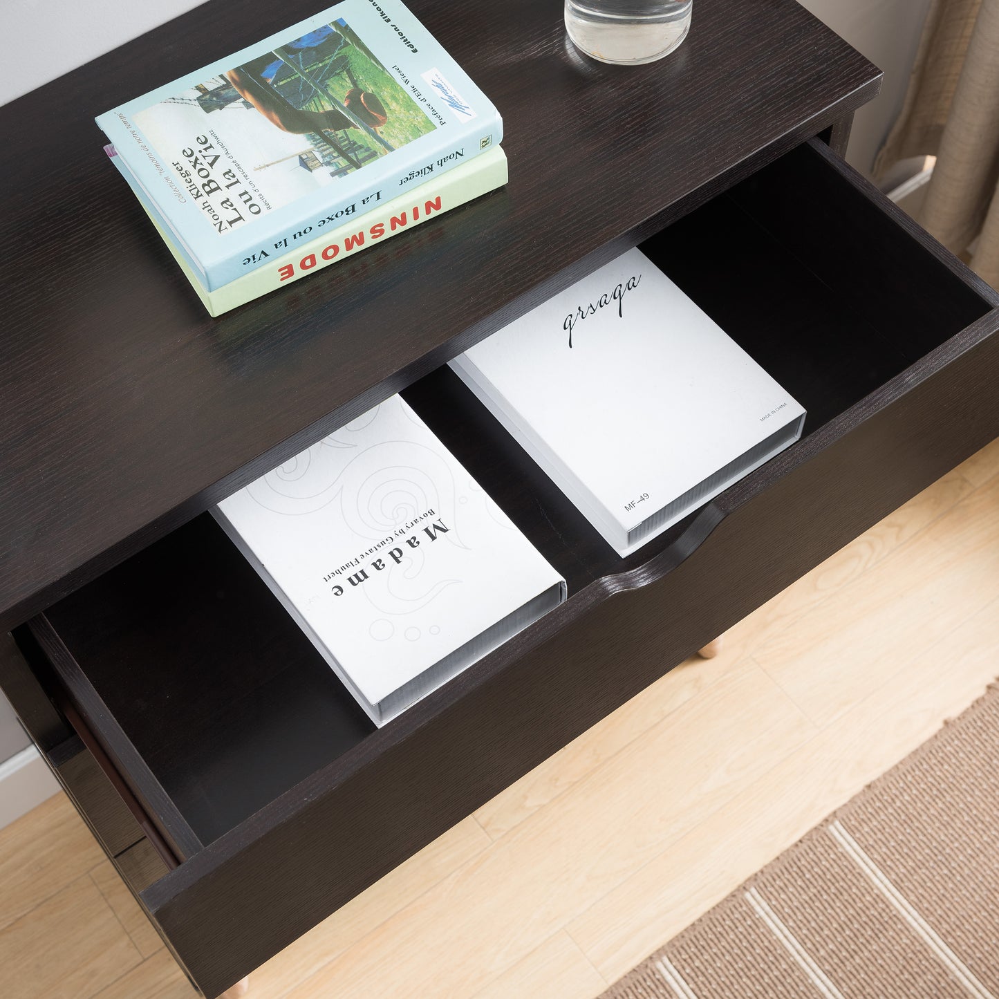 Right angled bird's eye close-up view of a mid-century modern cappuccino four-drawer chest dresser with top drawer open in a bedroom with accessories