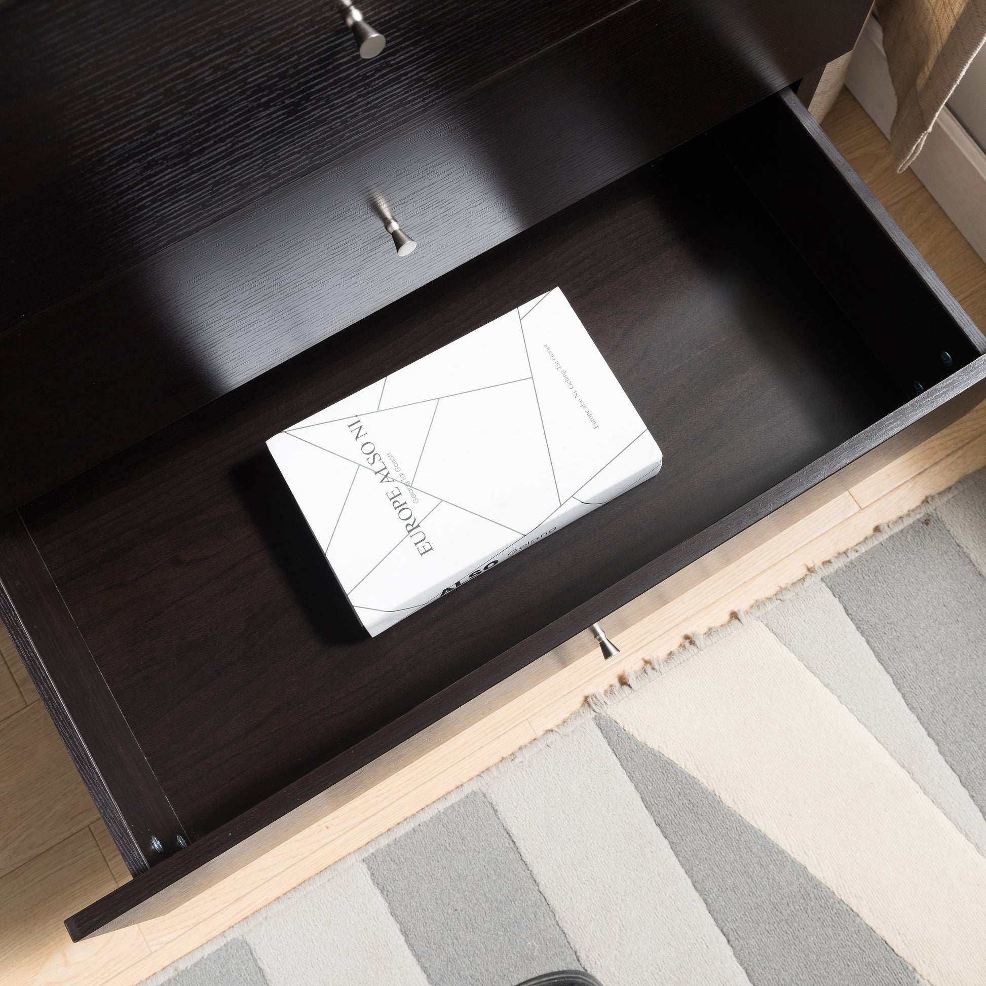 Right angled bird's eye close-up view of a mid-century modern cappuccino four-drawer chest dresser with top drawer open in a bedroom with accessories