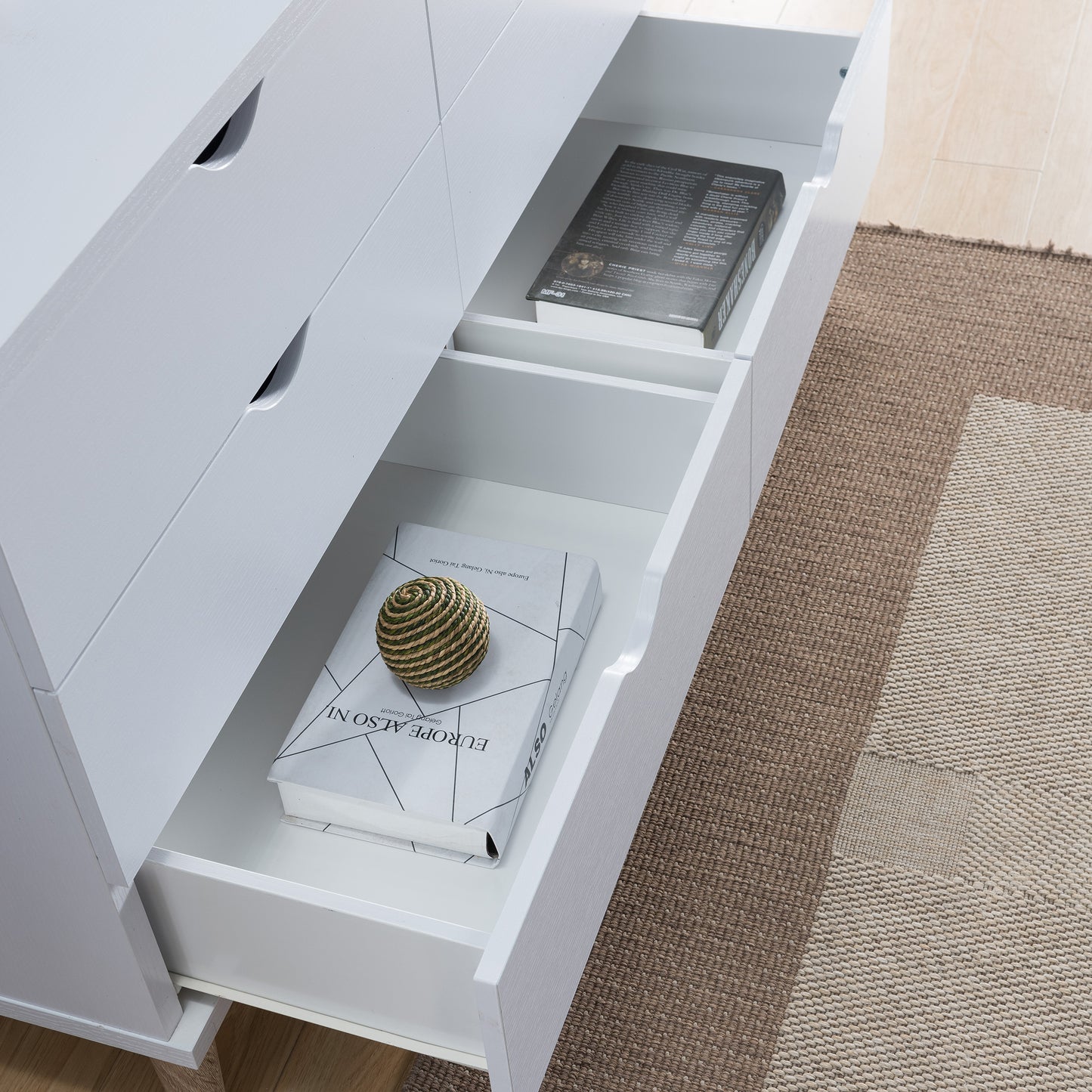 Right angled bird's eye close-up view of a mid-century modern white six-drawer dresser with bottom drawers open in a bedroom with accessories