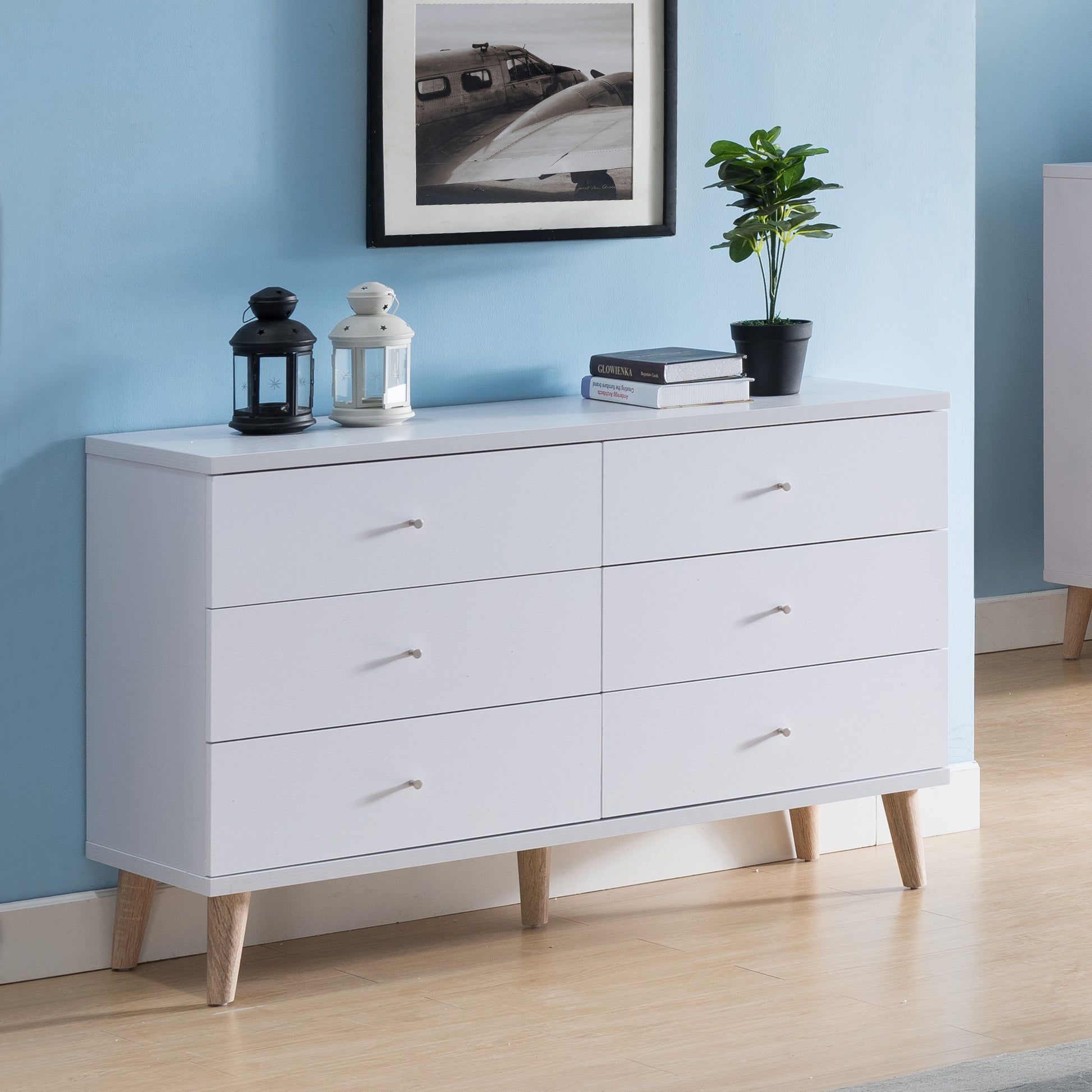 Right angled mid-century modern white six-drawer dresser in a bedroom with accessories