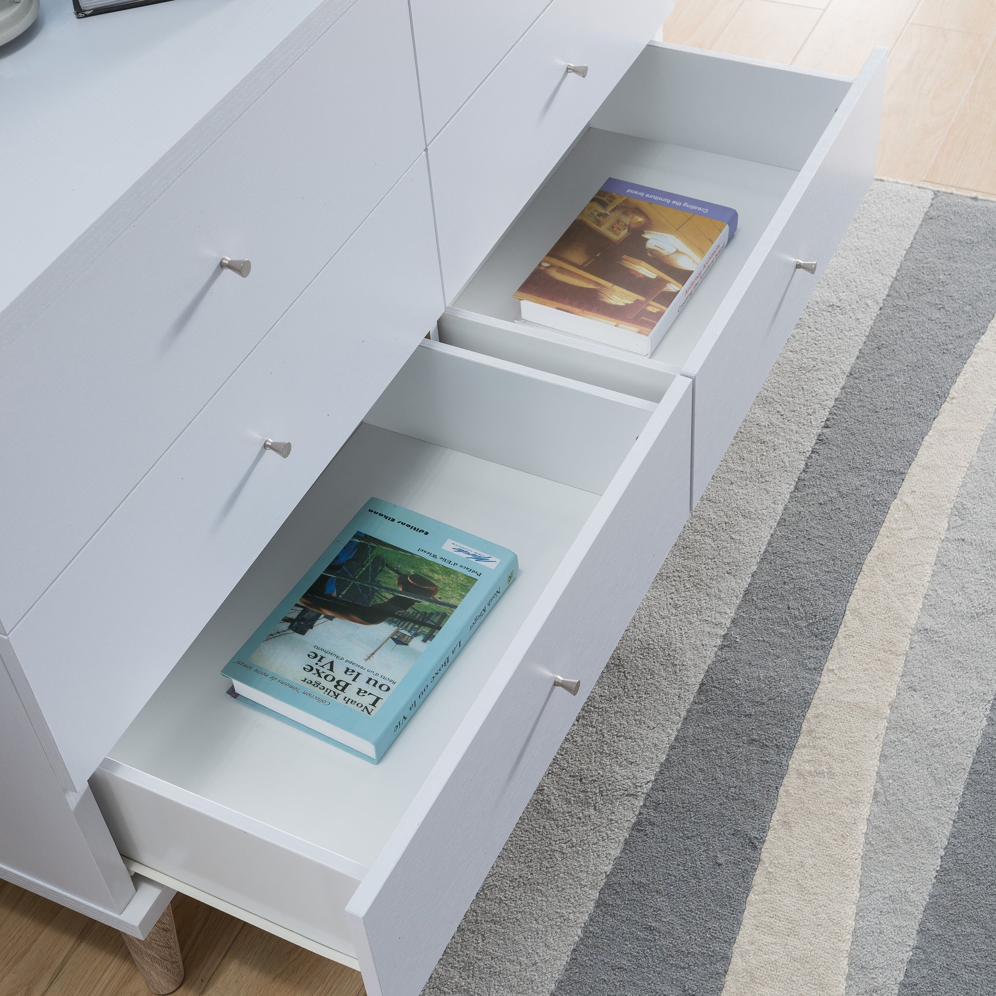 Right angled bird's eye close-up view of a mid-century modern white six-drawer dresser with bottom drawers open in a bedroom with accessories