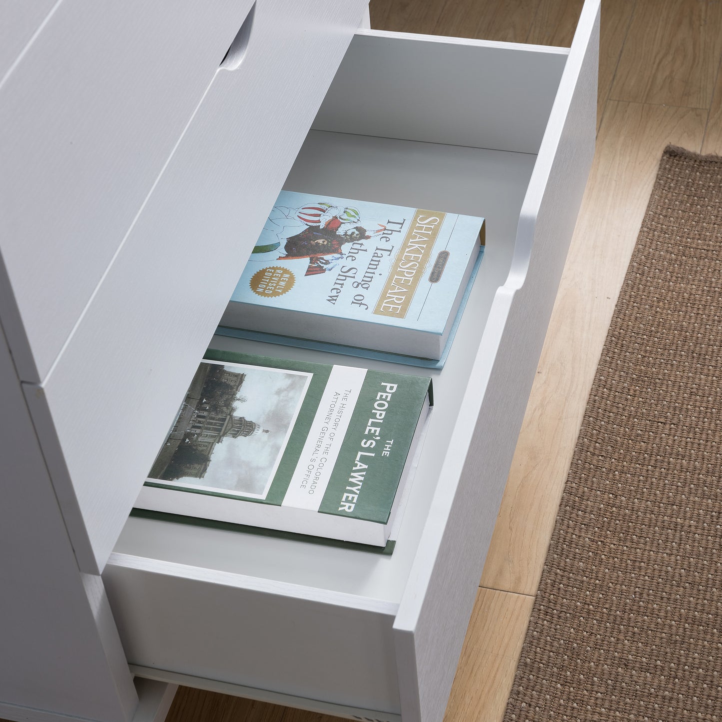 Right angled bird's eye close-up view of a mid-century modern white four-drawer chest dresser with the bottom drawer open in a bedroom with accessories