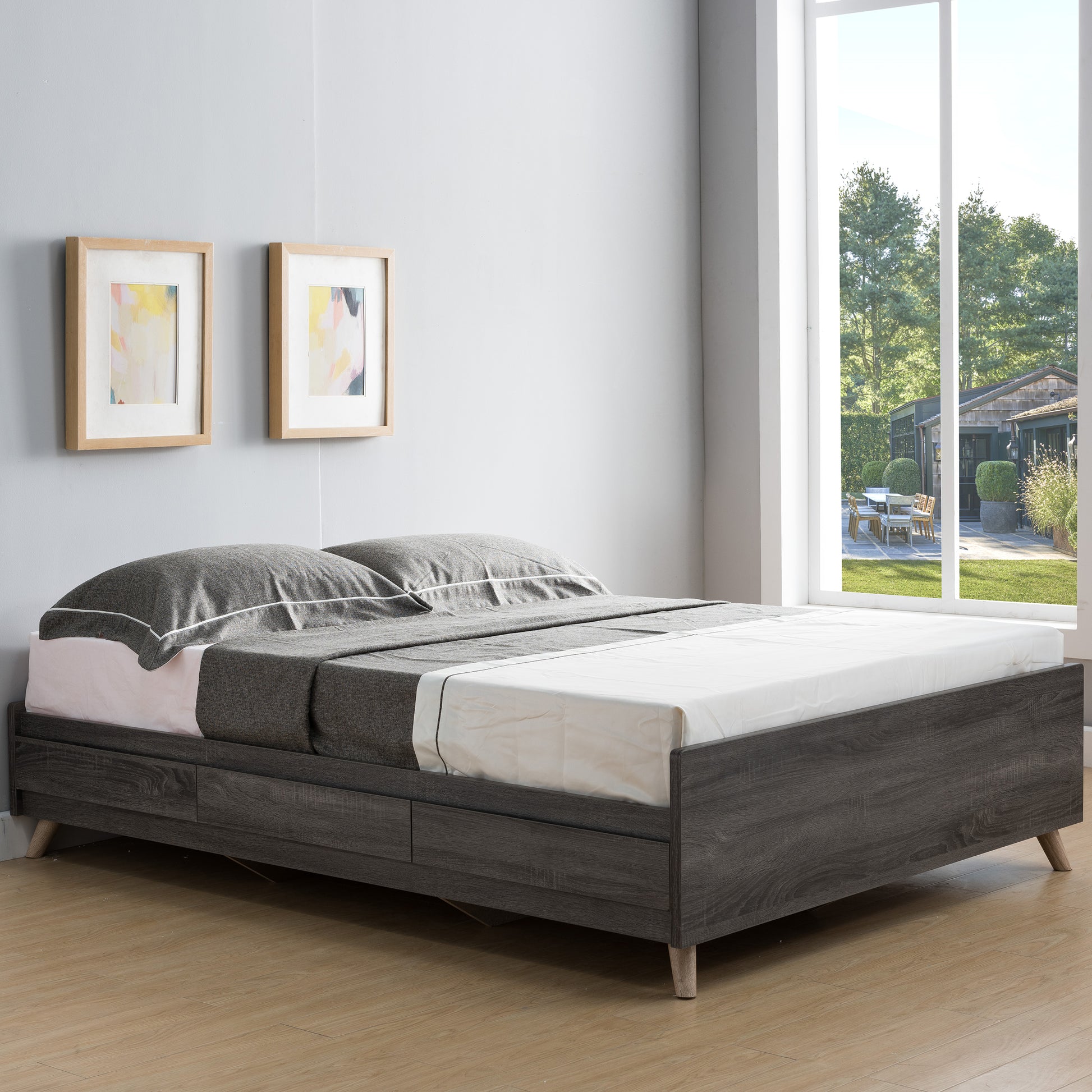 Right angled mid-century modern distressed gray platform storage bed with three drawers in a bedroom with linens and accessories