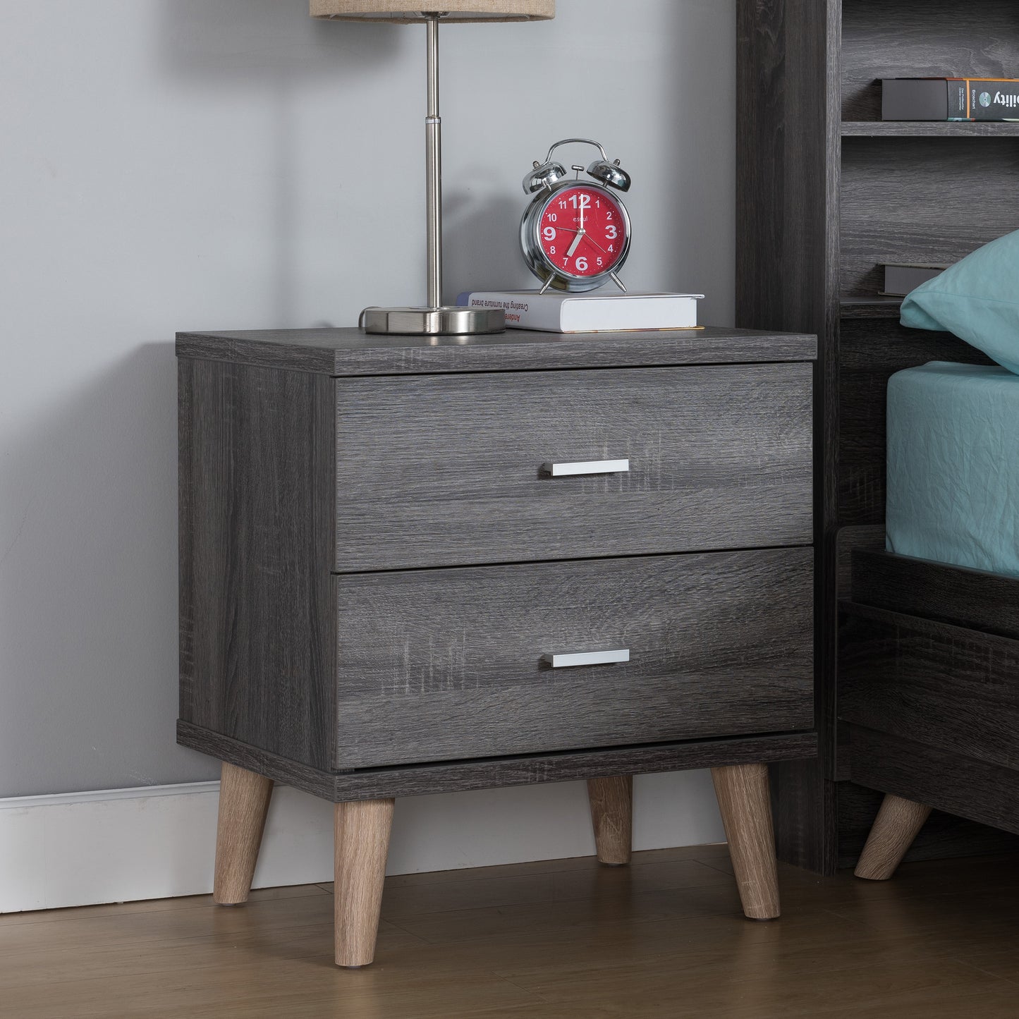 Right angled mid-century modern distressed gray two-drawer nightstand in a bedroom with accessories