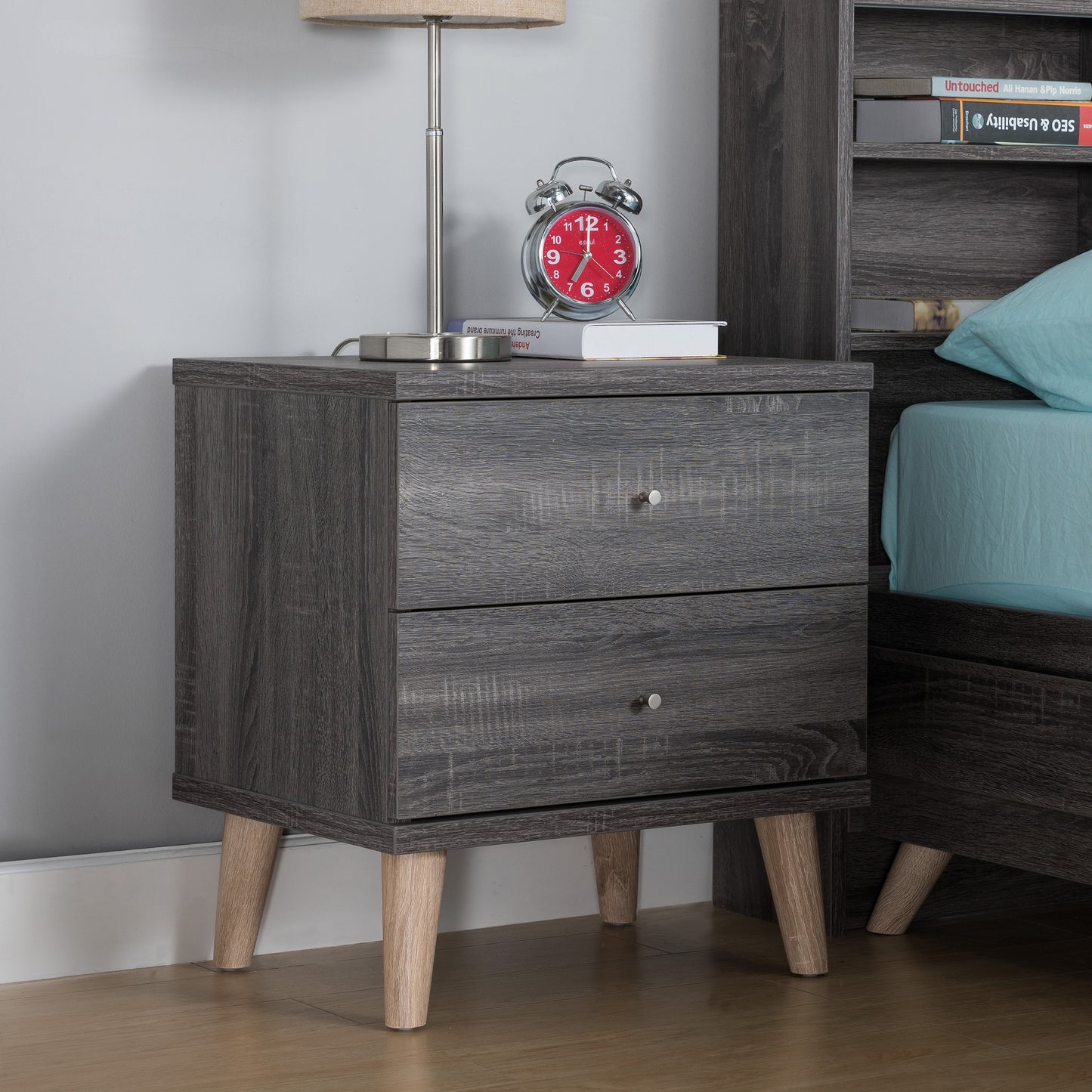 Right angled mid-century modern distressed gray two-drawer nightstand in a bedroom with accessories