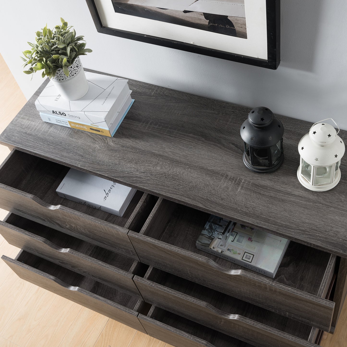 Left angled bird's eye close-up view of a mid-century modern distressed gray six-drawer dresser with all drawers open in a bedroom with accessories