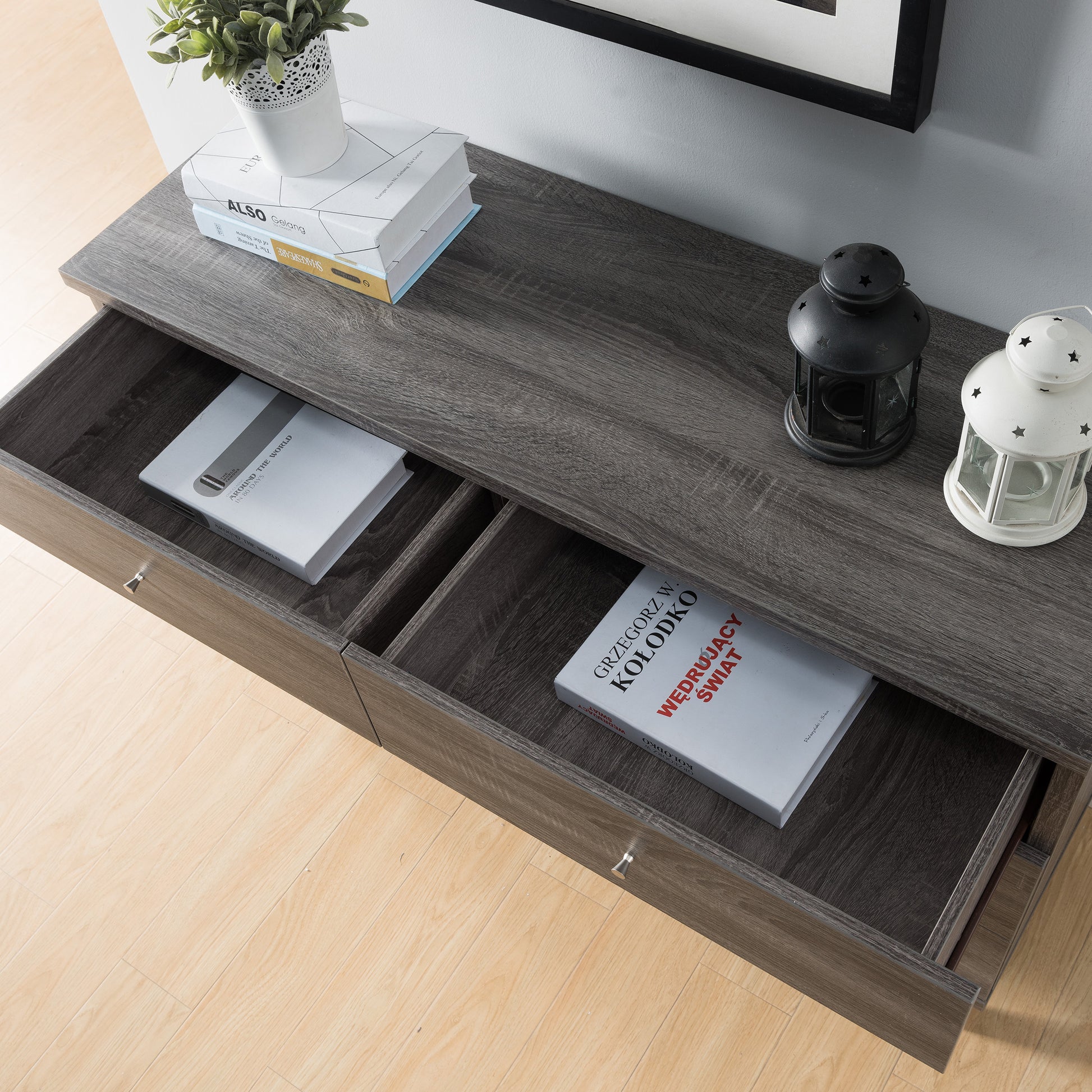 Left angled bird's eye close-up view of a mid-century modern distressed gray six-drawer dresser with top drawers open in a bedroom with accessories