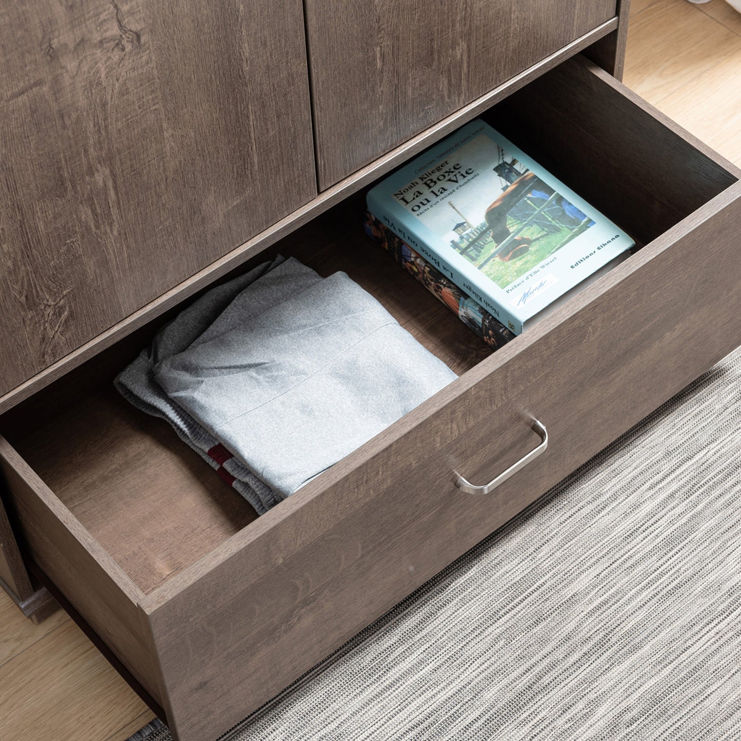 Right angled bird's eye view close-up of a contemporary walnut two-door one-drawer wardrobe armoire with drawer open in a bedroom with accessories