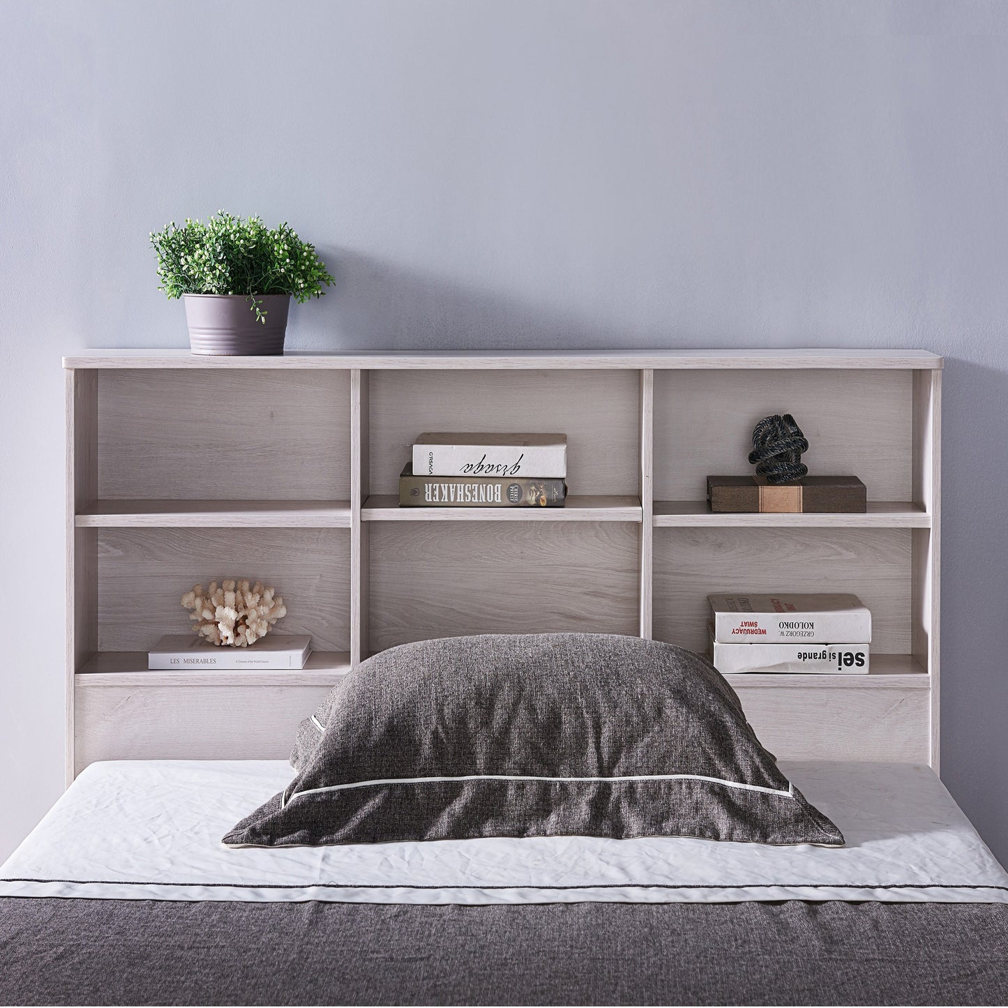 Front-facing transitional white oak six-shelf standing bookcase headboard shown with a bed in a bedroom with accessories